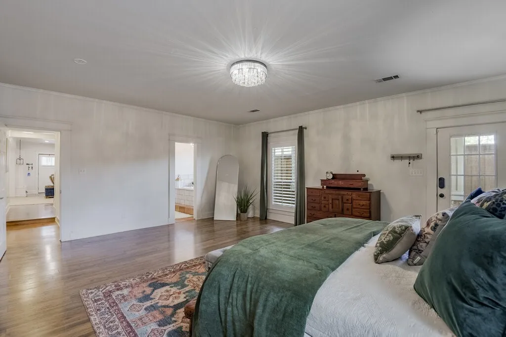 Spacious primary bedroom featuring hardwood flooring, recessed ceiling lighting, multiple windows with shutters providing natural light, and ample room accommodating substantial furnishings and décor placement