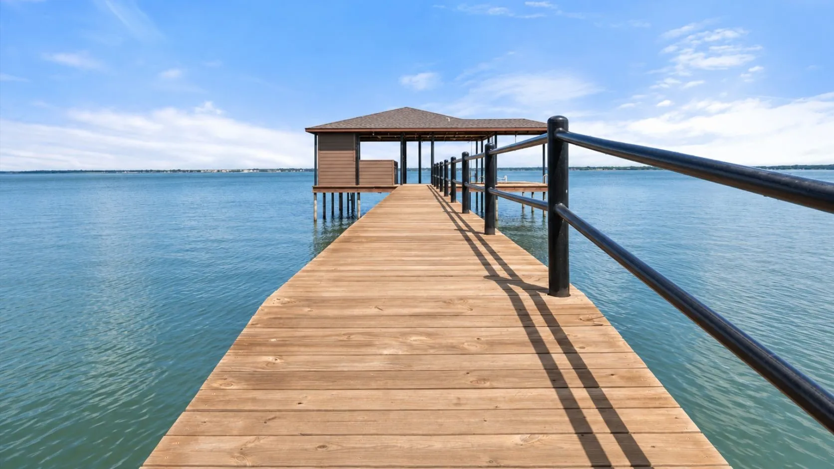 Long private dock stretches across beautiful open water, creating a front-row connection to the lake from 5042 Loper Circle.