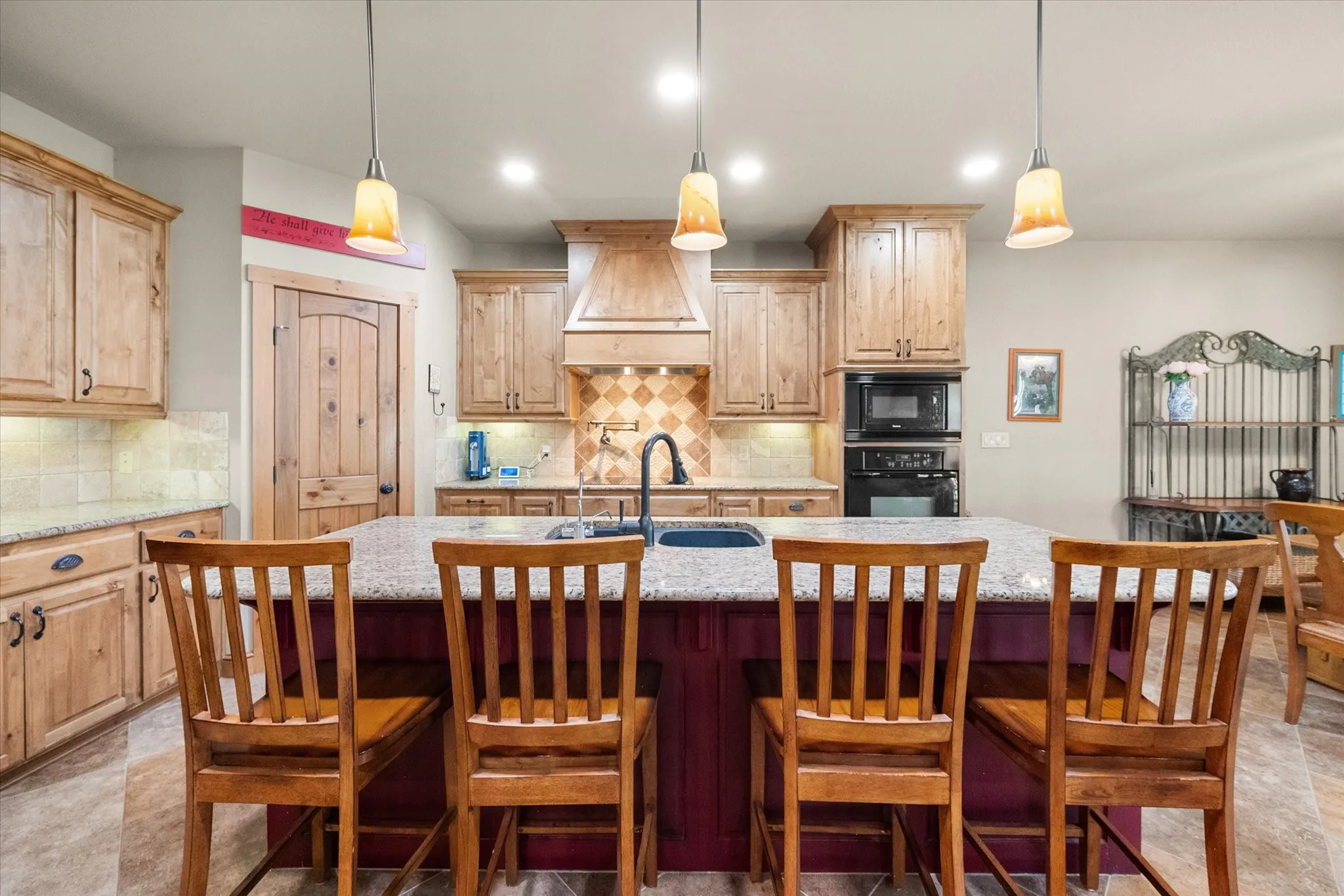 Spacious kitchen features extensive natural wood cabinetry, granite surfaces, a large island, and open access to the living and dining areas.