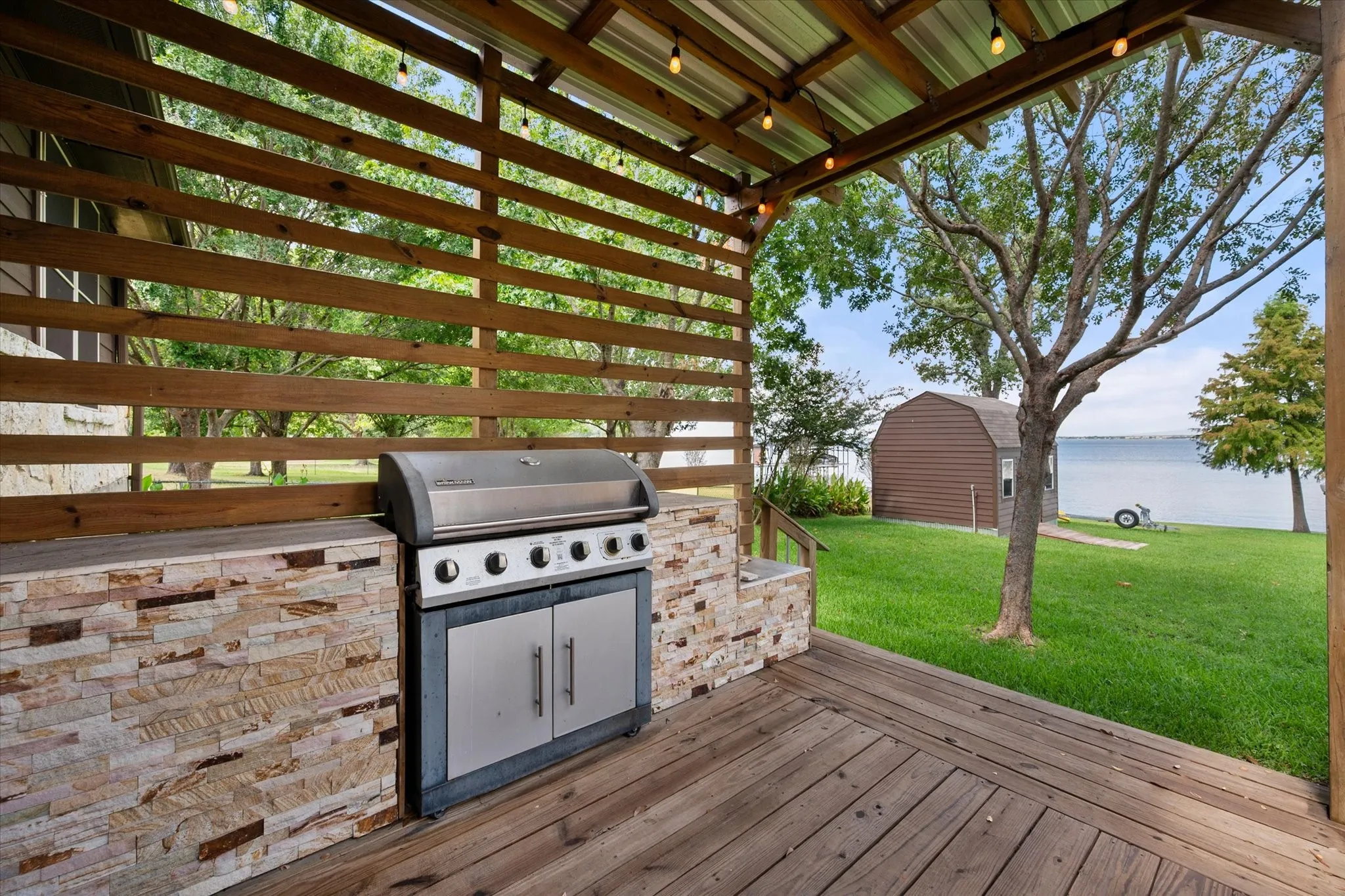 Dedicated covered grilling station creates a convenient outdoor cooking space just steps from the lake and backyard.
