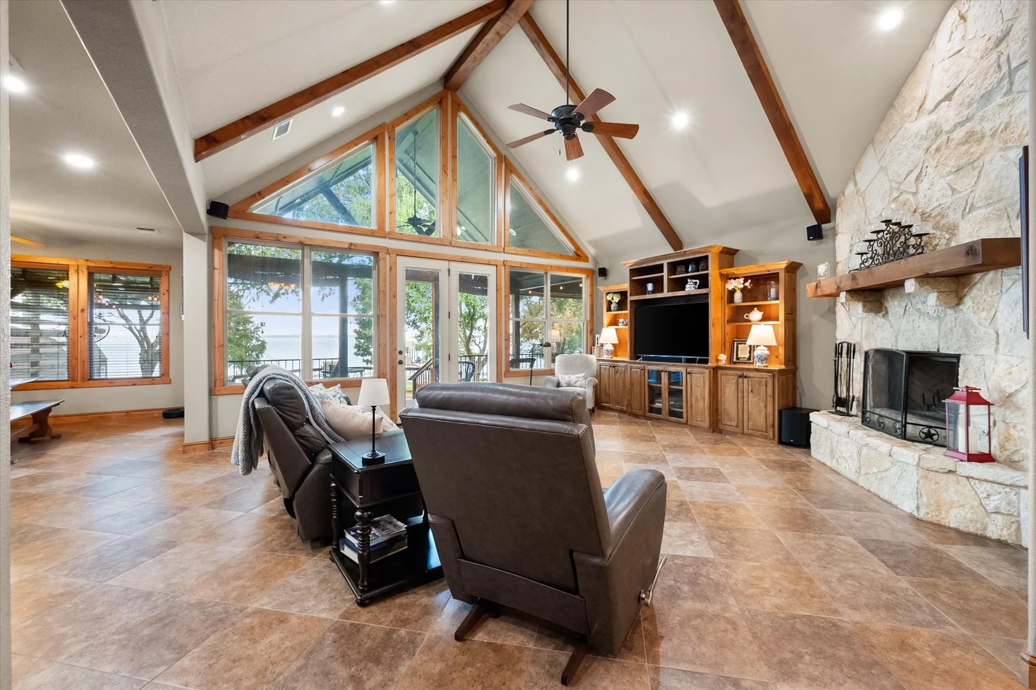 Spacious great room combines soaring ceilings, abundant natural light, and a stone fireplace for comfortable lakefront living.