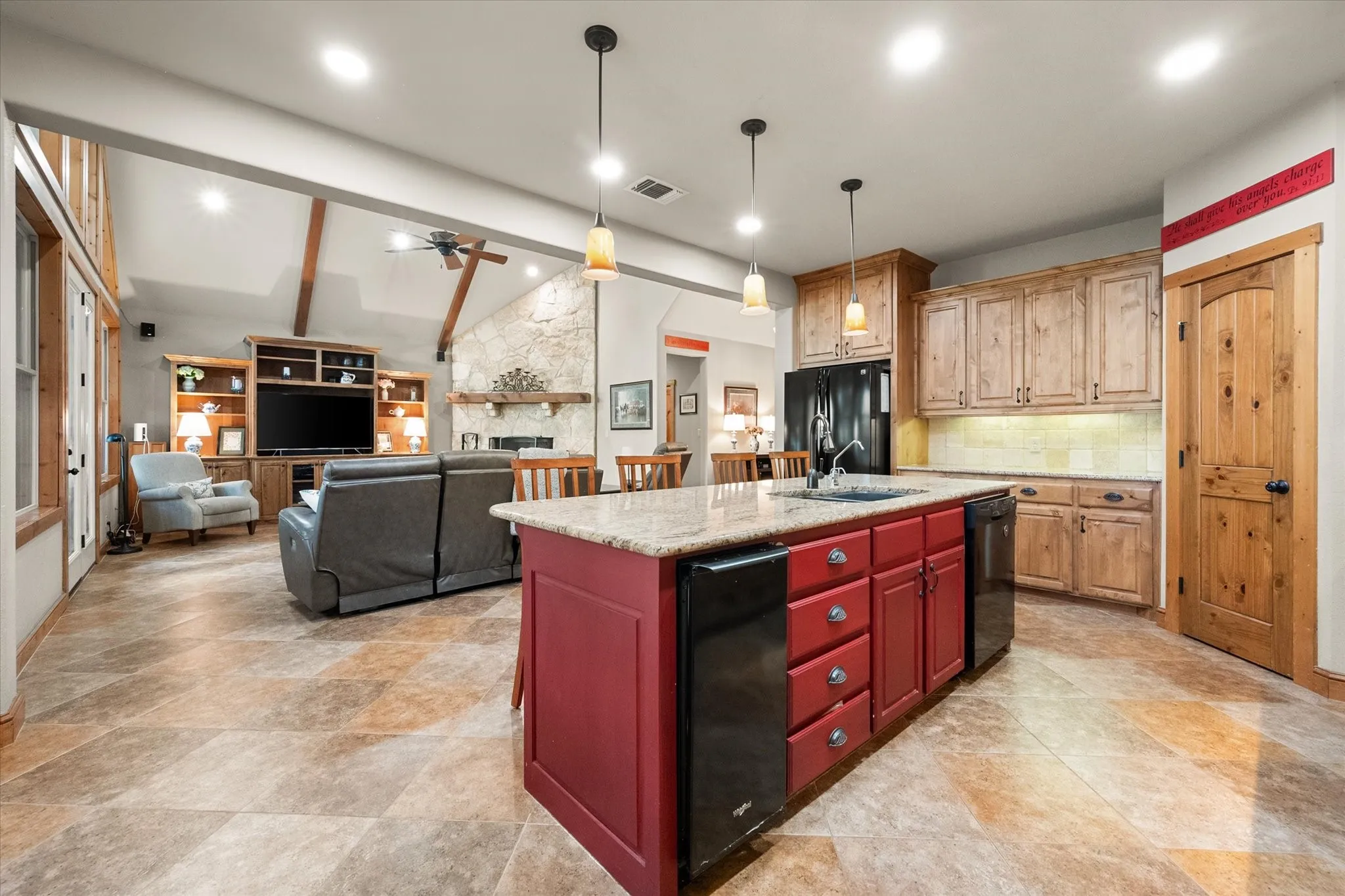 Spacious open-concept kitchen at 5042 Loper Circle features a large center island, granite countertops, abundant natural wood cabinetry, pendant lighting, and seamless flow into the living area of this Streetman, Texas waterfront home.