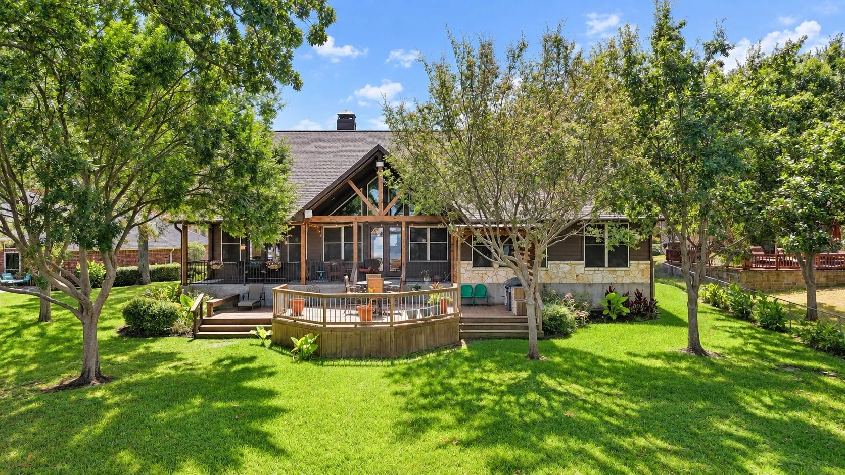 Lush backyard with mature shade trees creates a beautiful transition from the home to its waterfront setting.