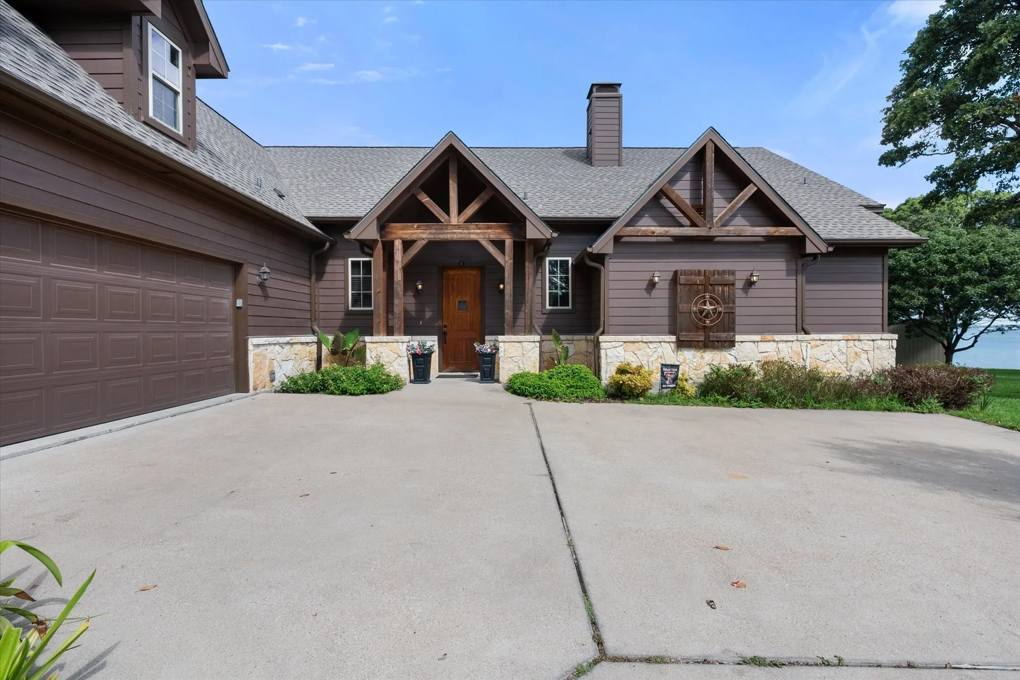 Inviting waterfront home at 5042 Loper Circle in Streetman, Texas, featuring expansive outdoor living beneath mature shade trees.