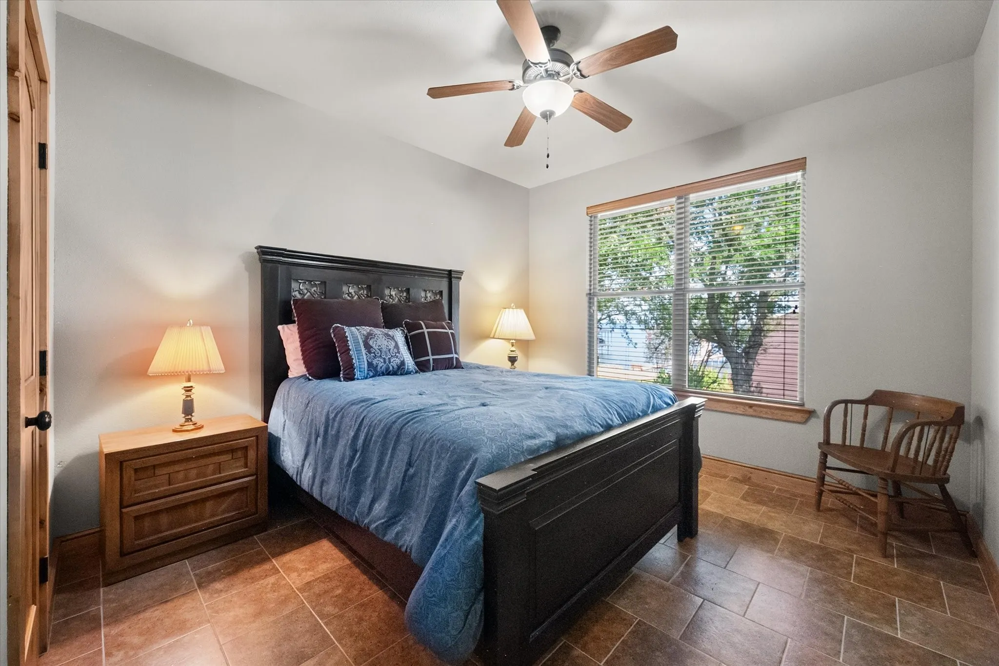 Bright secondary bedroom offers peaceful views, tile flooring, ceiling fan, and a comfortable layout for family or guests.