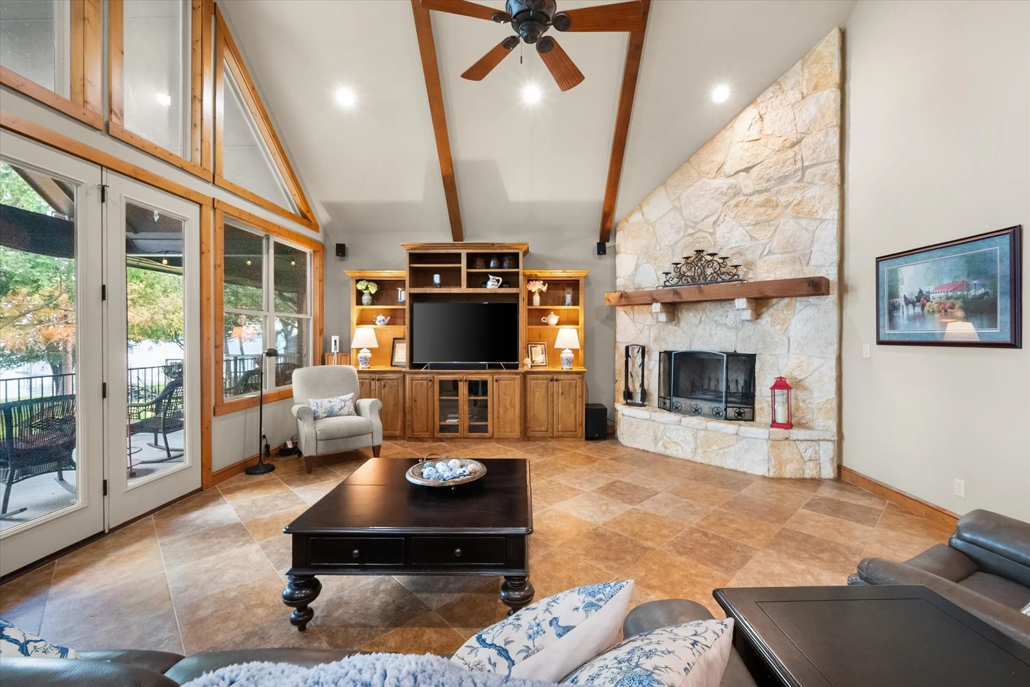 Floor-to-ceiling stone fireplace anchors the open living room beneath striking vaulted ceilings with warm architectural details.
