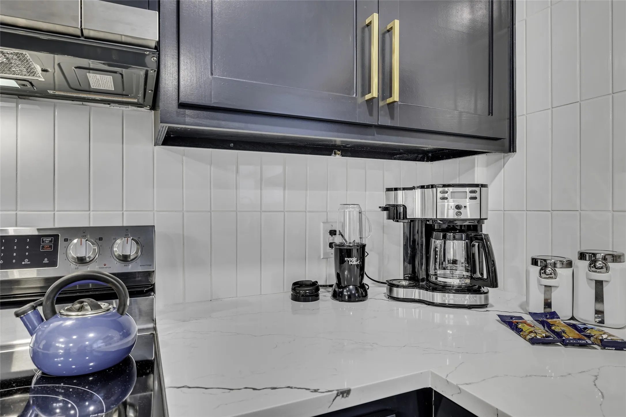 Kitchen view of light stone counters, backsplash, extractor fan, washer / dryer, and electric range