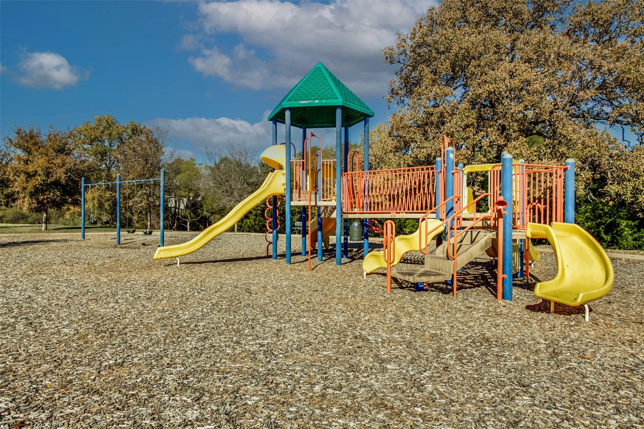 Playground area featuring multiple slides, a climbing structure, and swings