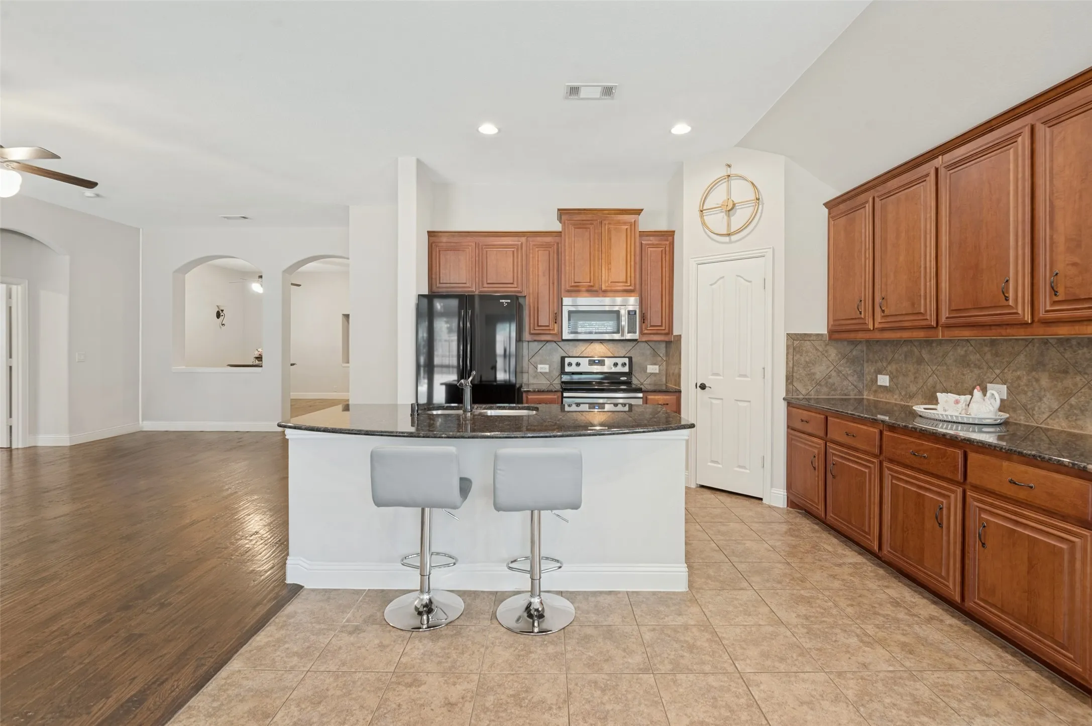 Kitchen featuring wood cabinetry, dark countertops, a tile backsplash, and recessed lighting
