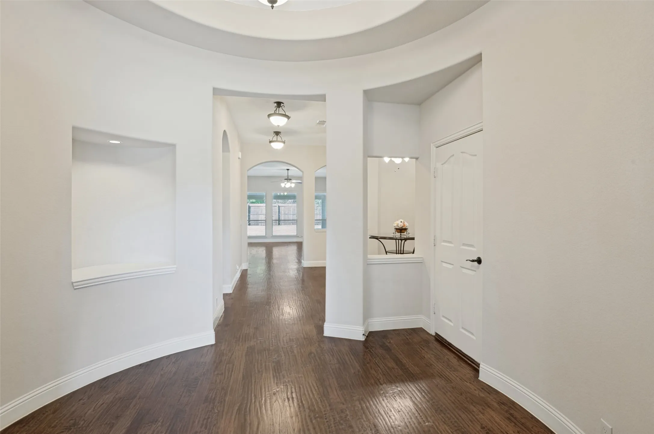 Archways throughout, wood-finish flooring, recessed wall niche, built-in shelf, and ceiling-mounted light fixtures