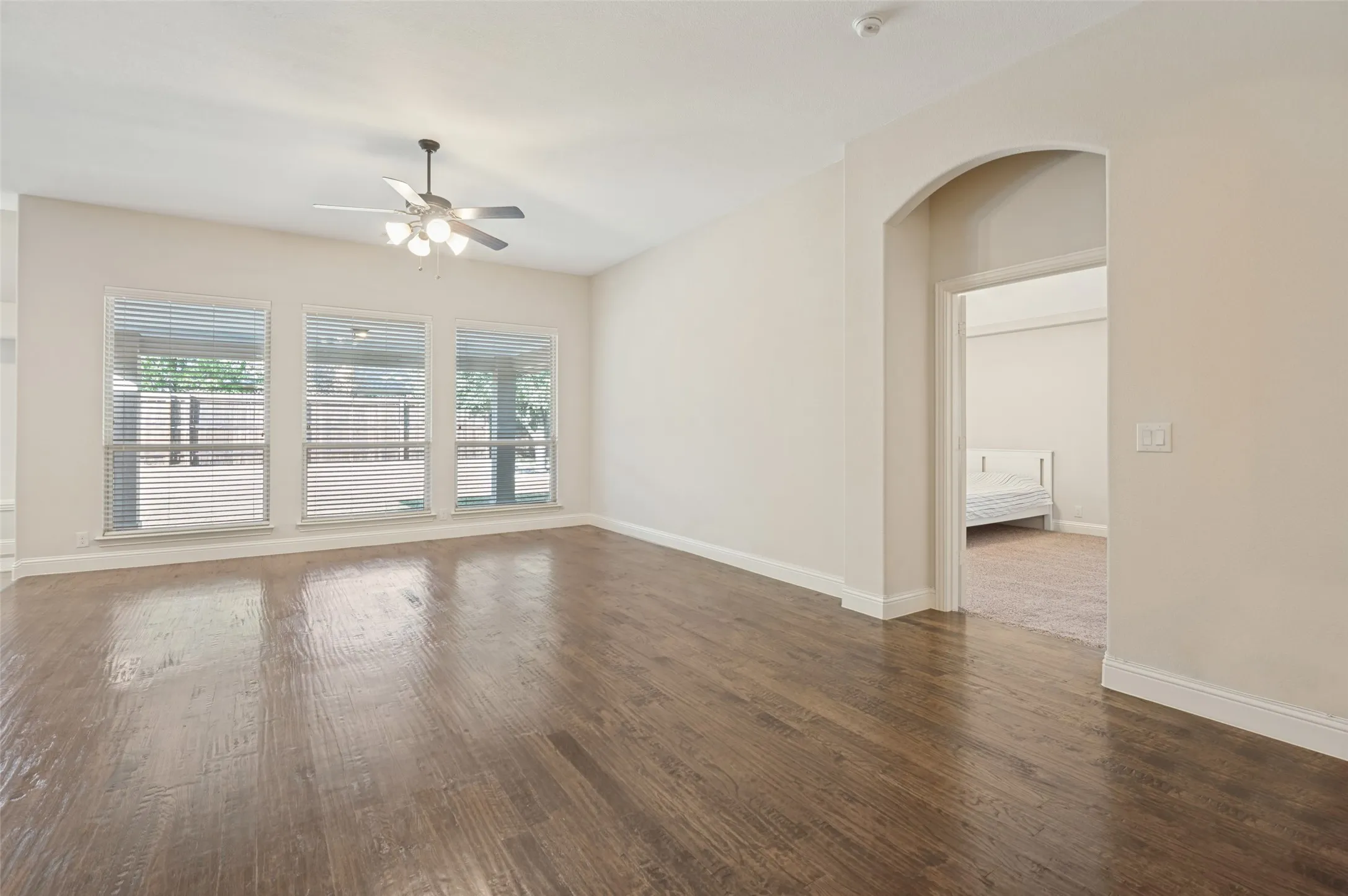 Hand scraped Hardwood floorsthroughout, featuring a ceiling fan with integrated lighting, and three large windows