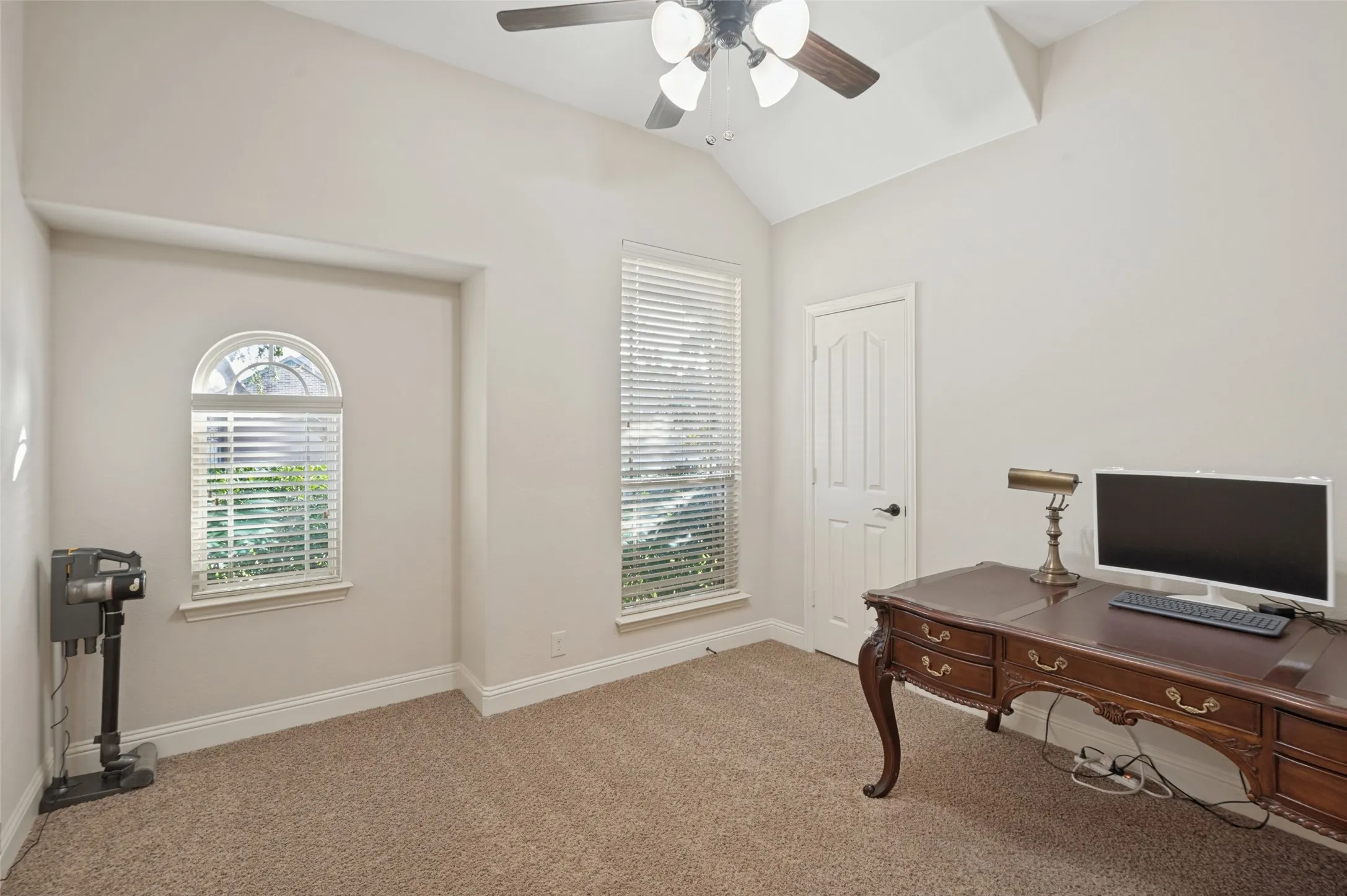 Vaulted ceiling with a ceiling fan, carpeted flooring, and two windows with blinds