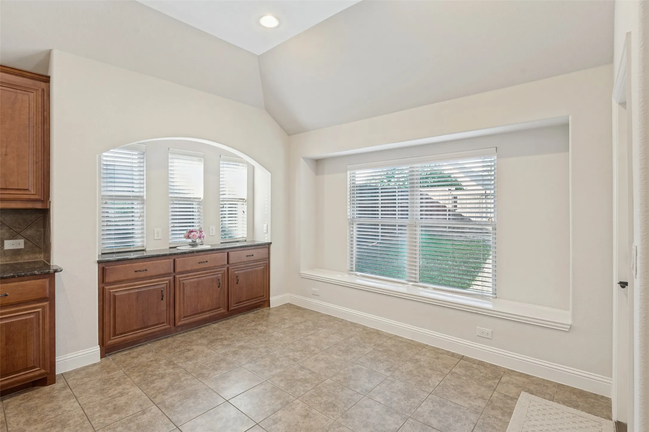 Arched wall niche with built-in cabinetry, granite countertop, and multiple windows