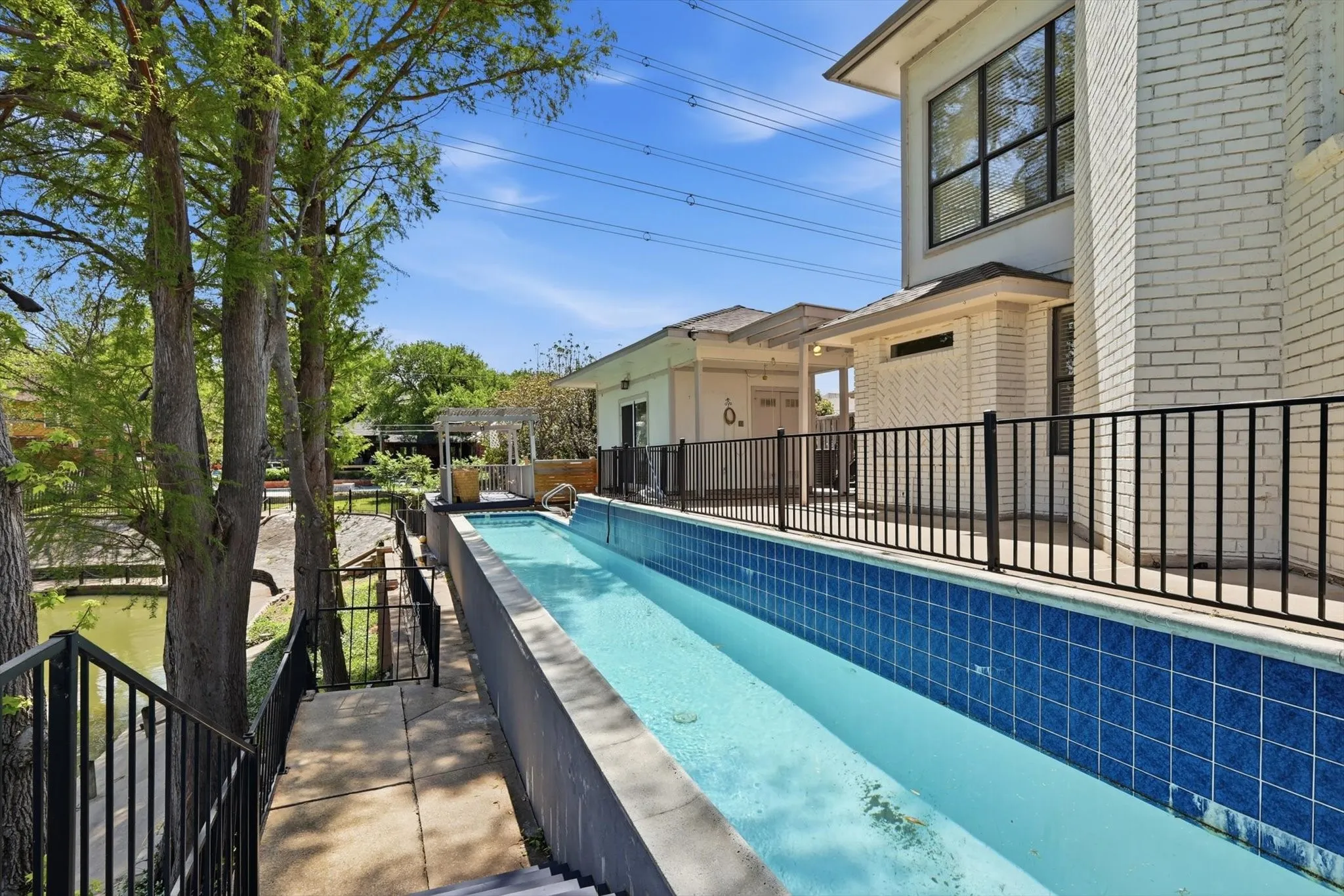 Elevated lap pool with blue tile surround, brick exterior, and multi-level outdoor access
