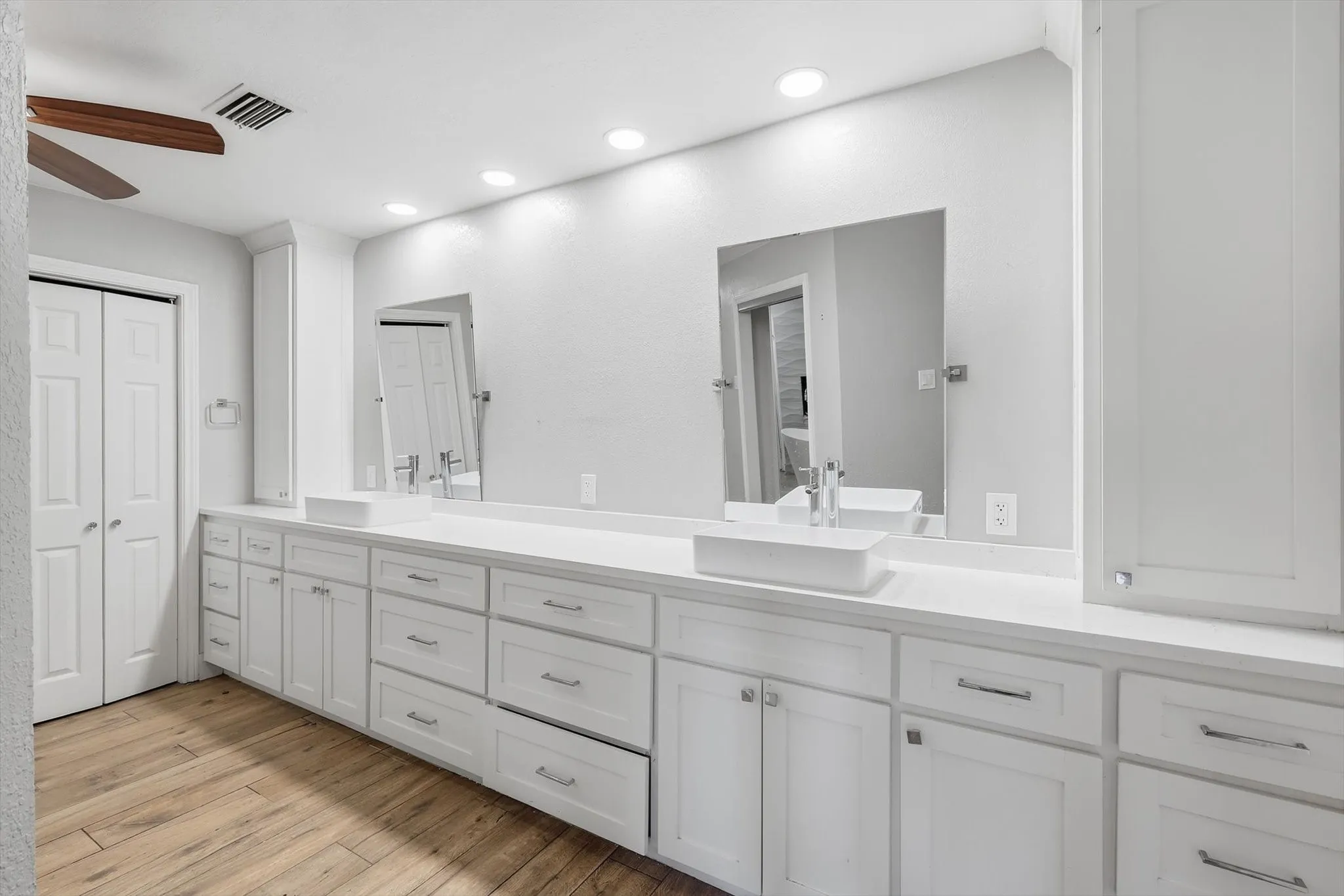 Extended dual vanity with white cabinetry and integrated vessel sinks
