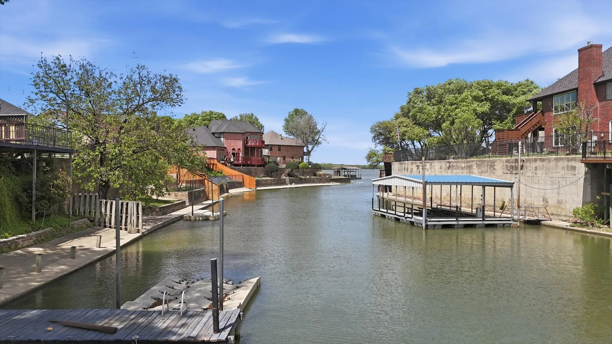 Waterfront property featuring a private boat dock, built-in boat slip with canopy, concrete retaining walls, and multi-level outdoor access