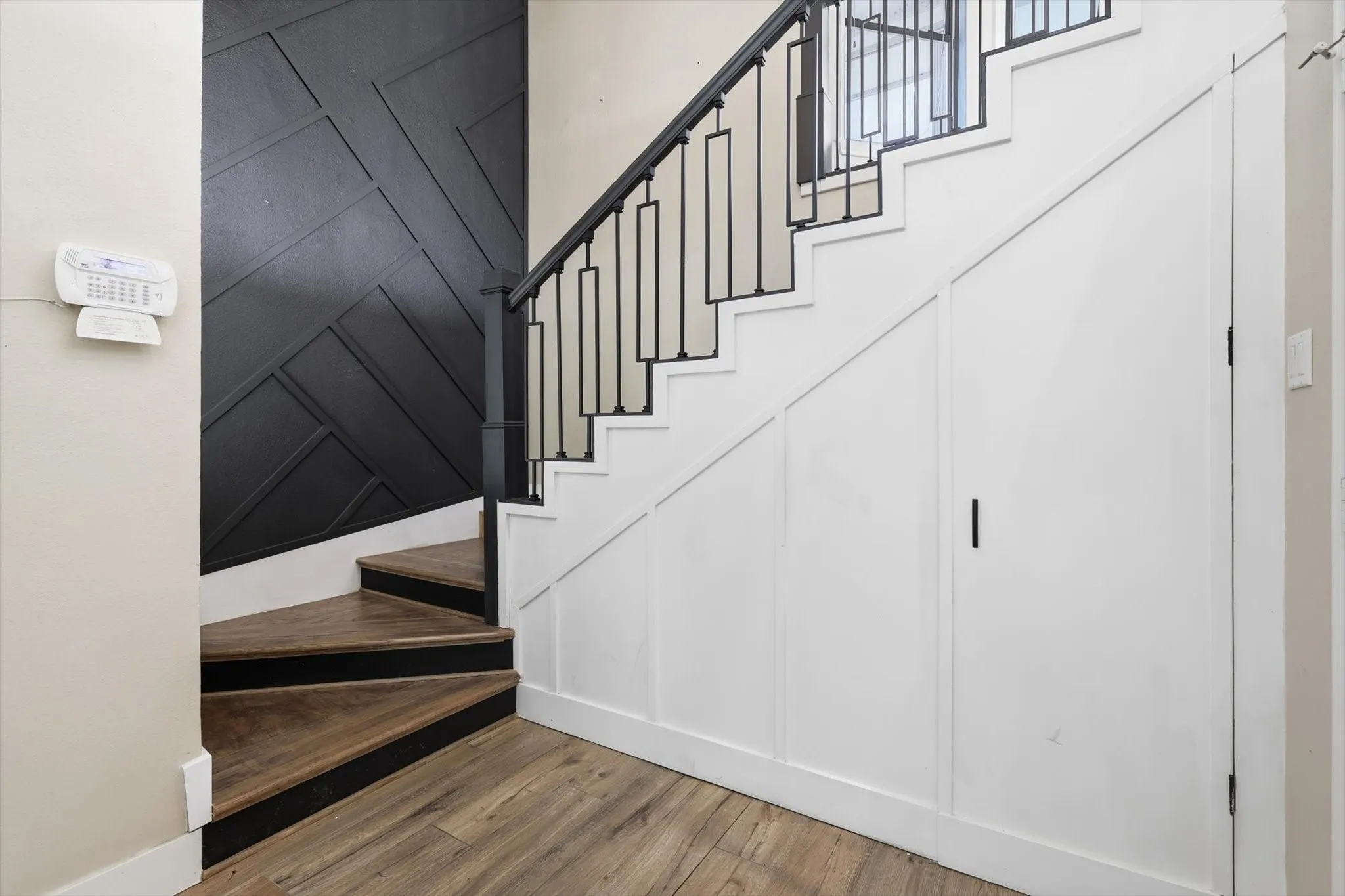 Wood-finish flooring with a multi-level staircase featuring black metal railings and white risers