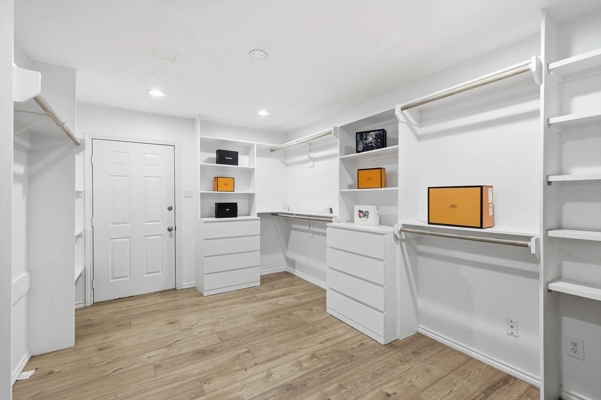Custom closet system featuring wood-finish flooring, recessed lighting, built-in shelving, and integrated drawer storage