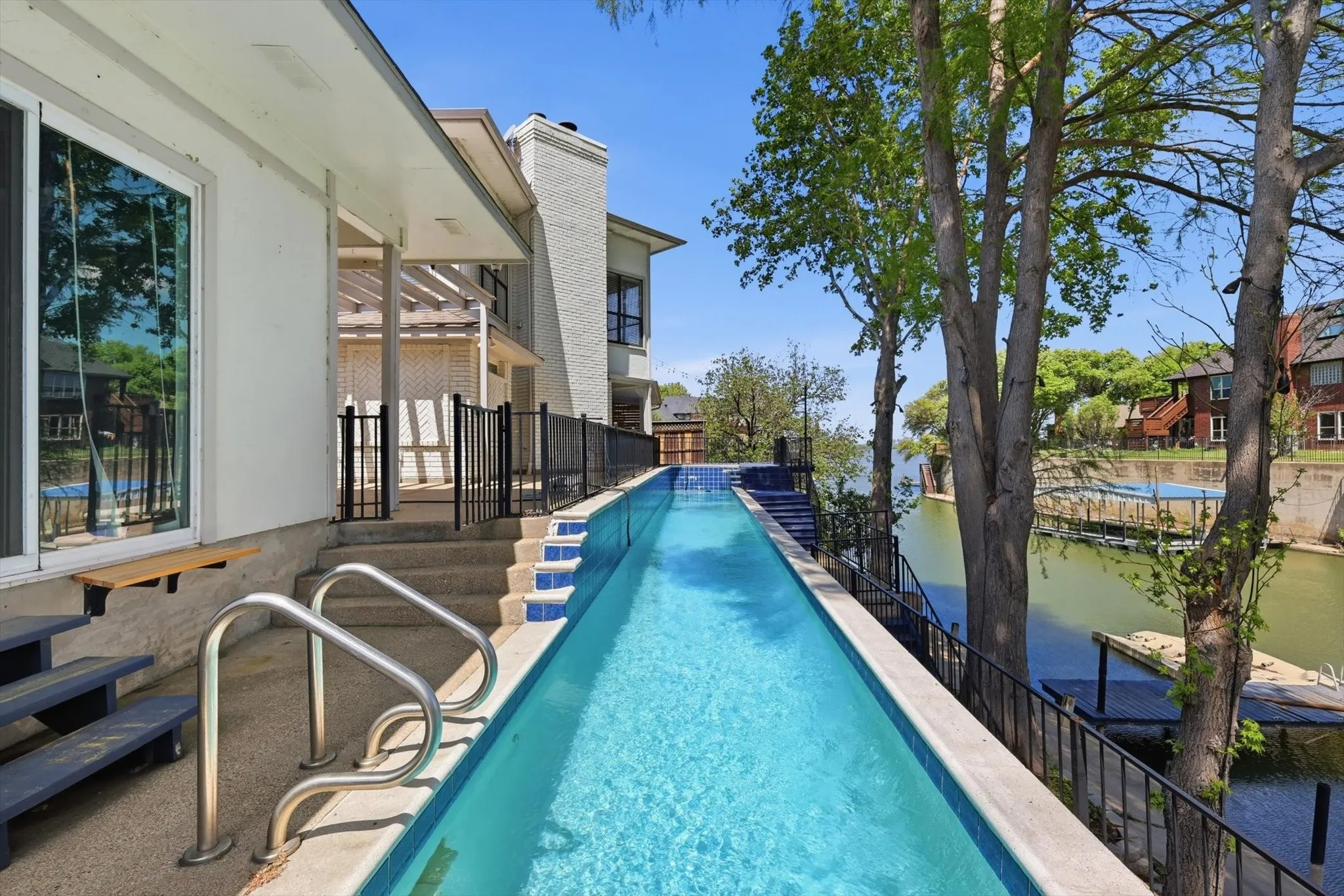 Infinity-edge swimming pool with integrated stairs and handrails, complemented by a private dock with direct water access