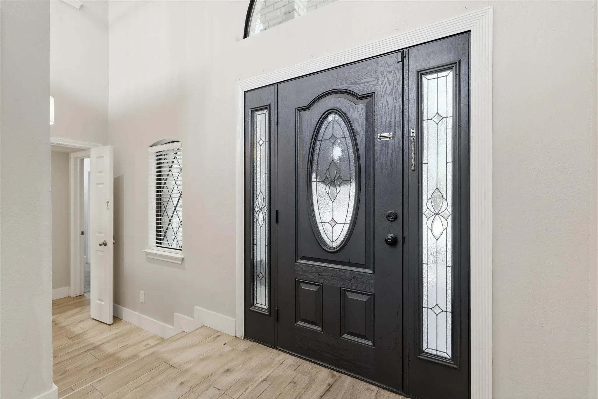 Double entry door with decorative glass inserts and transom, flanked by a leaded glass sidelight