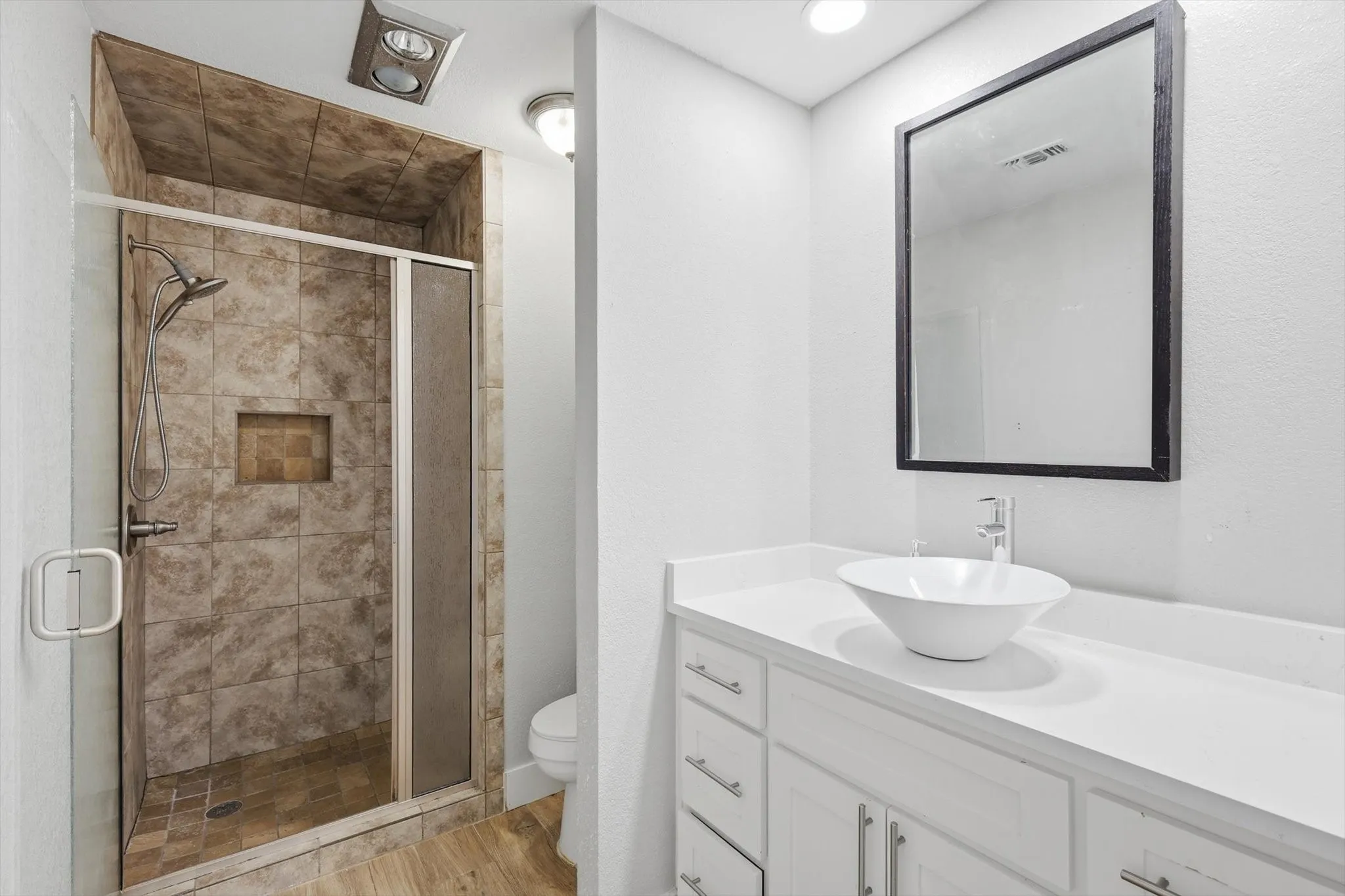 Tiled shower with a built-in niche, glass enclosure, and mounted showerhead