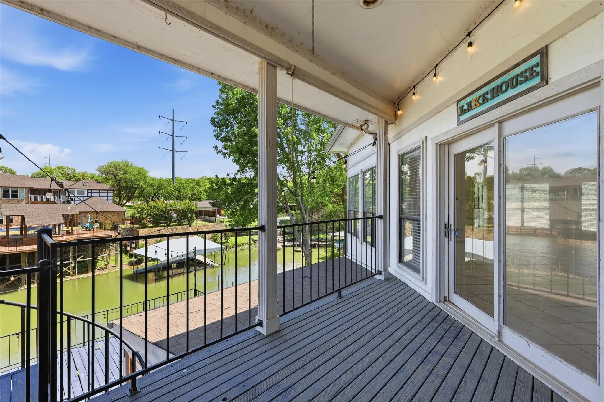 Covered outdoor deck with grey composite decking, black metal railings, and dual paned glass doors