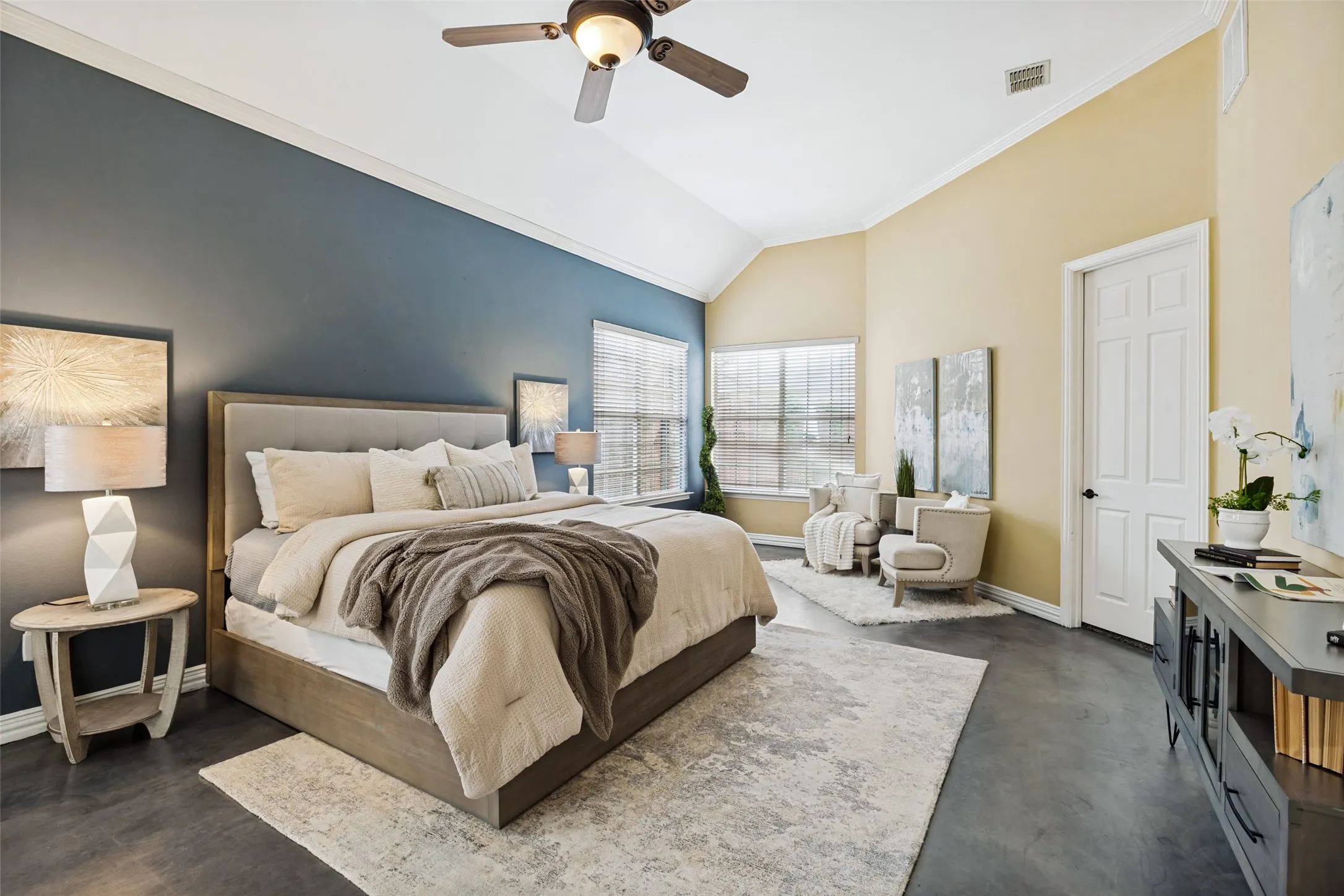 Vaulted ceiling with ceiling fan, ample natural light from multiple windows, dark wood-finish flooring, and a paneled door