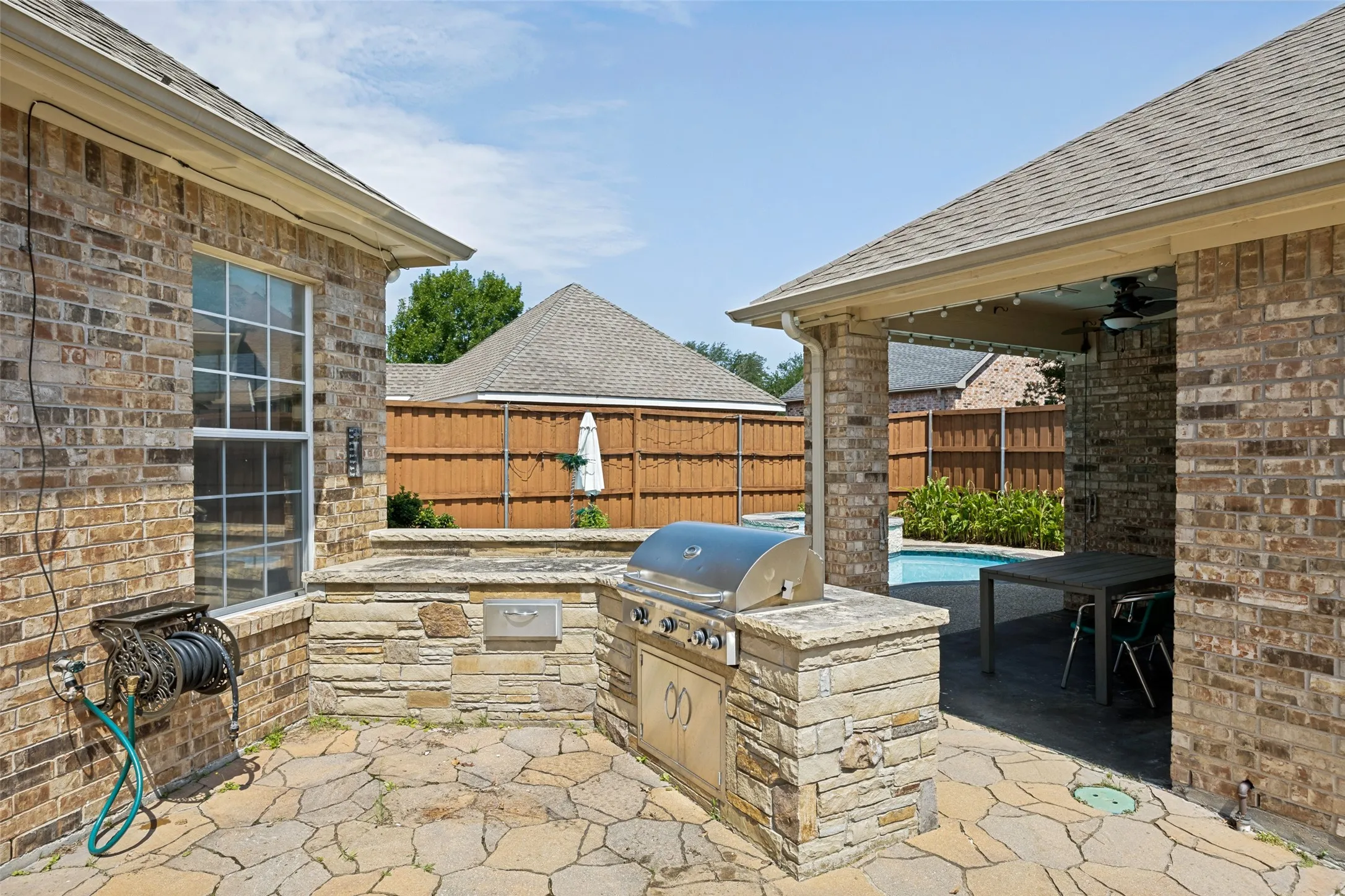 Brick exterior with a built-in outdoor kitchen, stone patio, covered patio, and swimming​​‌​​​​‌​​‌‌​‌‌​​​‌‌​‌​‌​‌​​​‌​​ pool