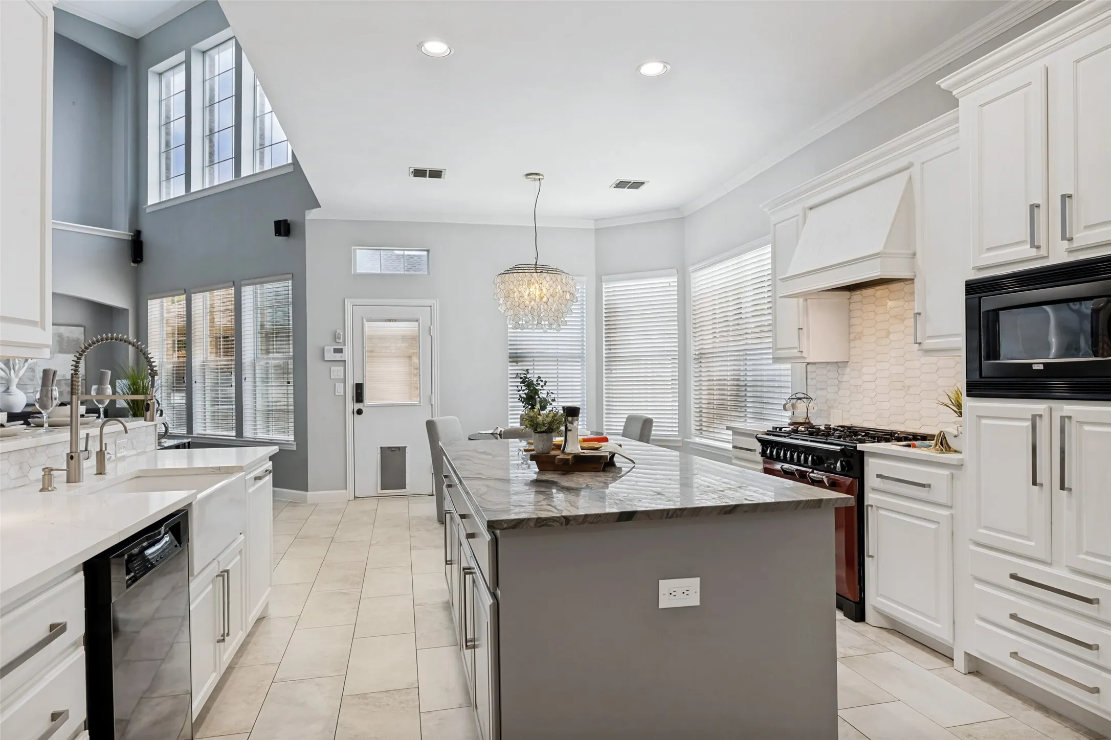 Kitchen featuring a large island with a stone countertop, white cabinetry, a built-in microwave, and a gas range