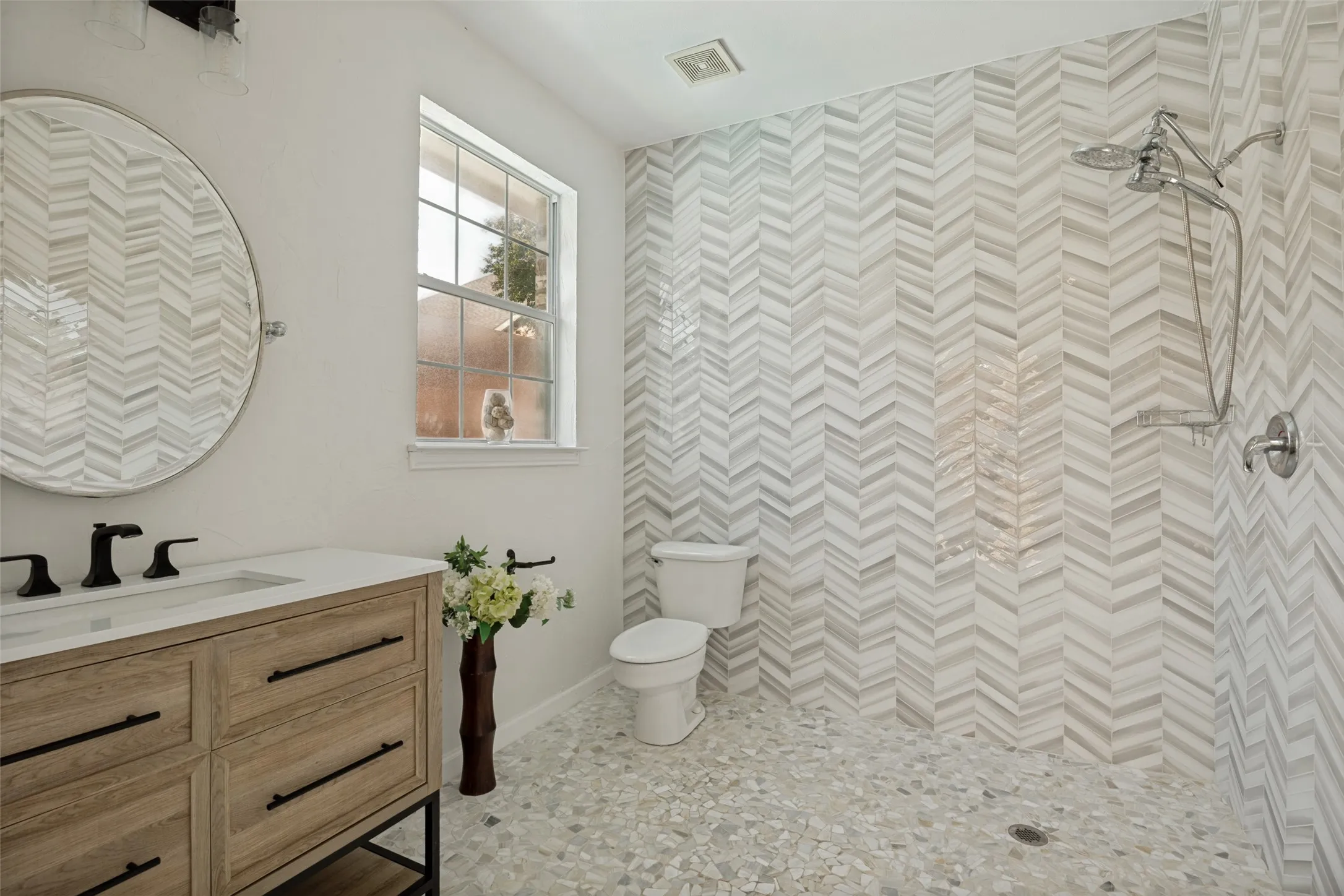 Herringbone tile wall in a walk-in shower, complemented by a dual shower head system