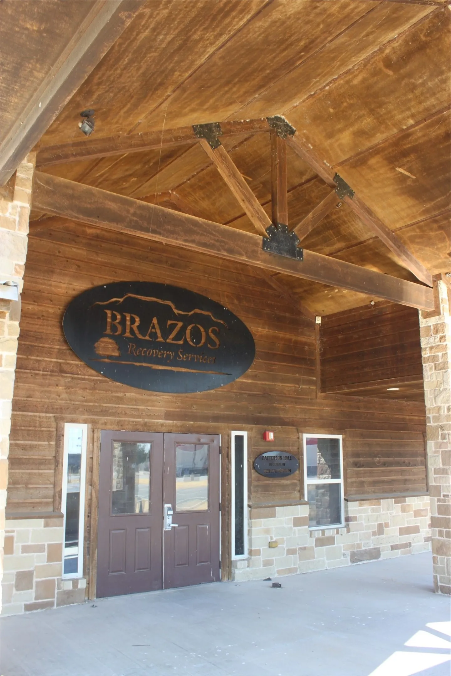 Brazos features a distinctive wood-shingled exterior with exposed timber beam detailing and a covered entrance