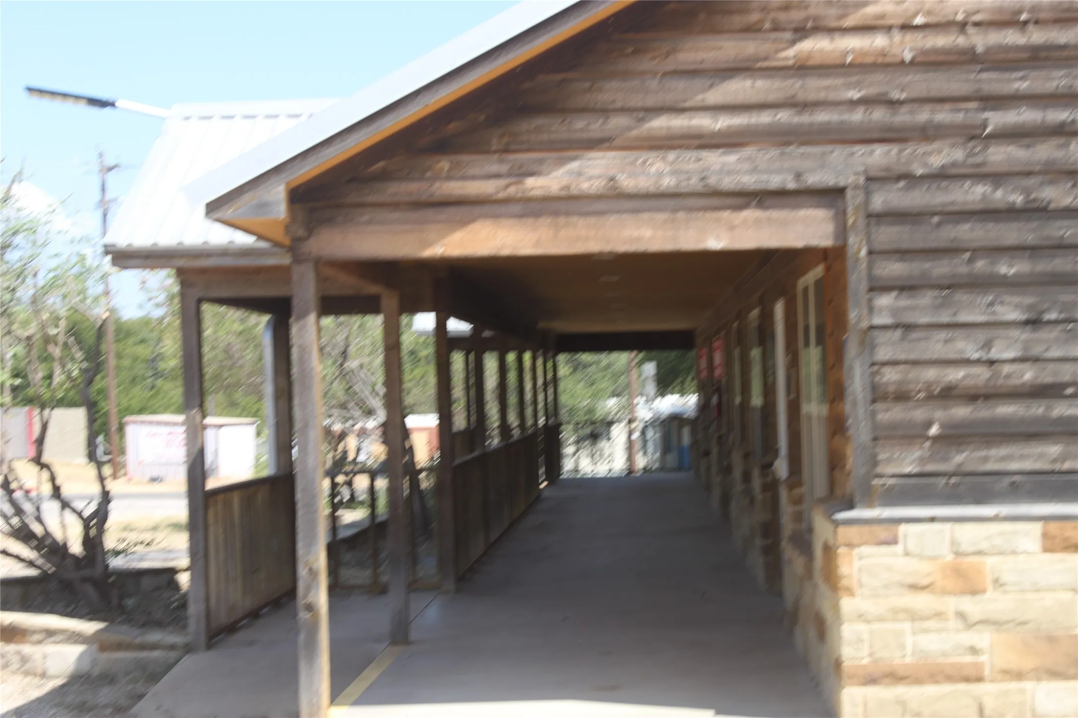 Covered breezeway with wood beam construction and wooden railings, offering sheltered outdoor passage