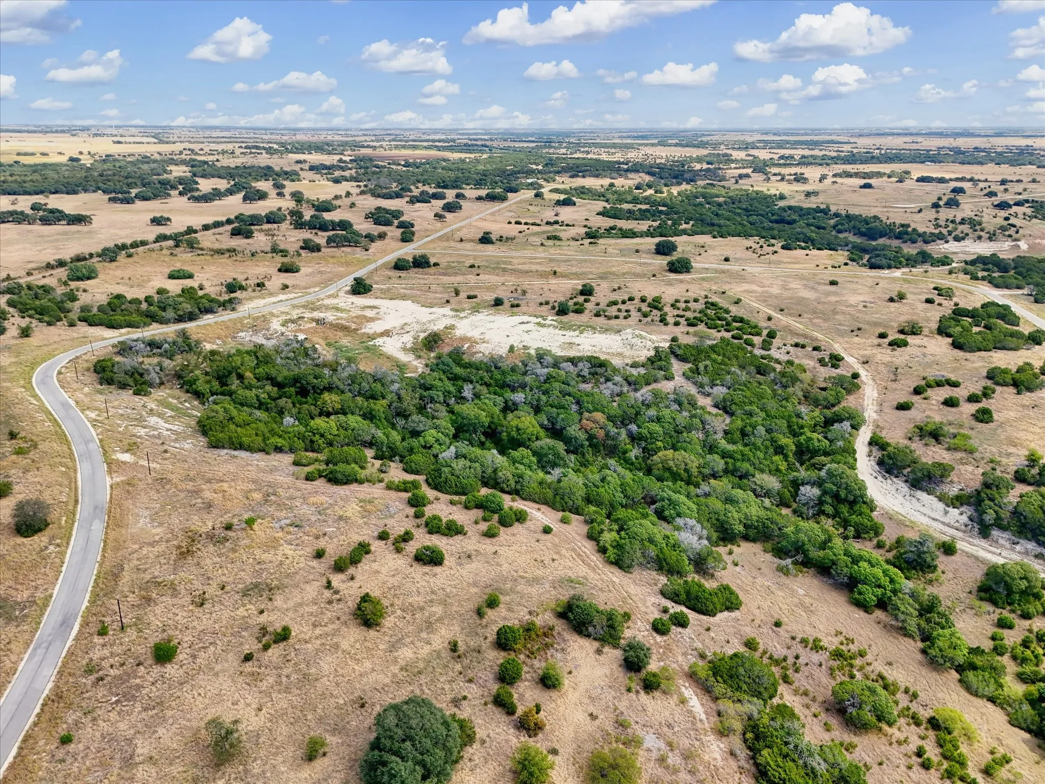 Expansive undeveloped land featuring natural foliage and a paved road