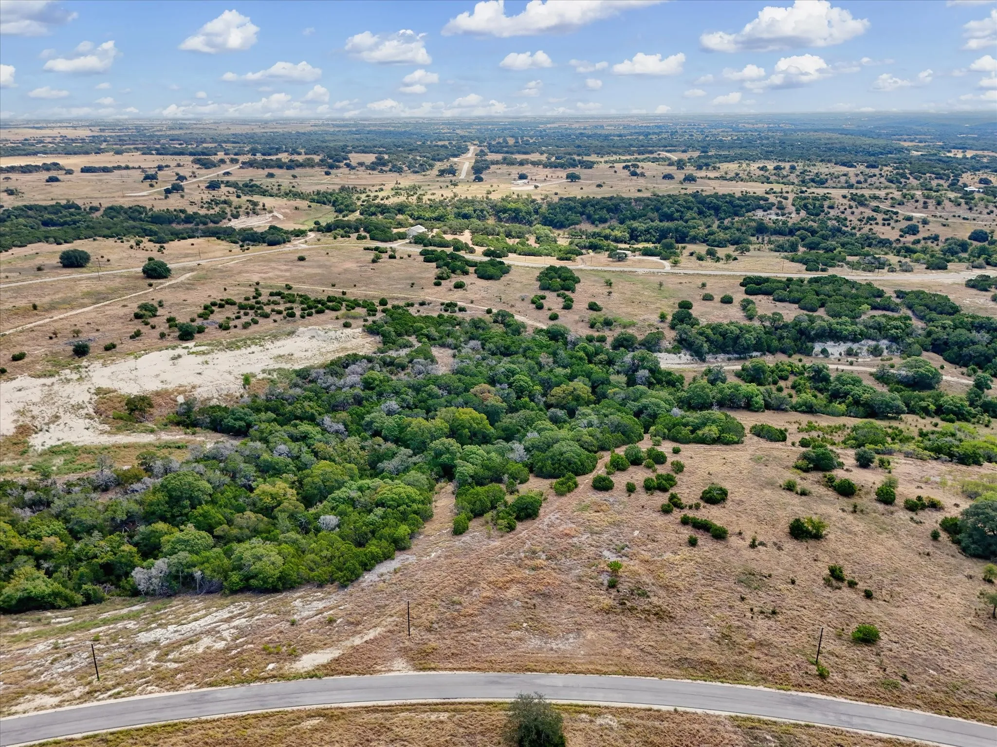 Expansive undeveloped land featuring diverse vegetation and a paved road