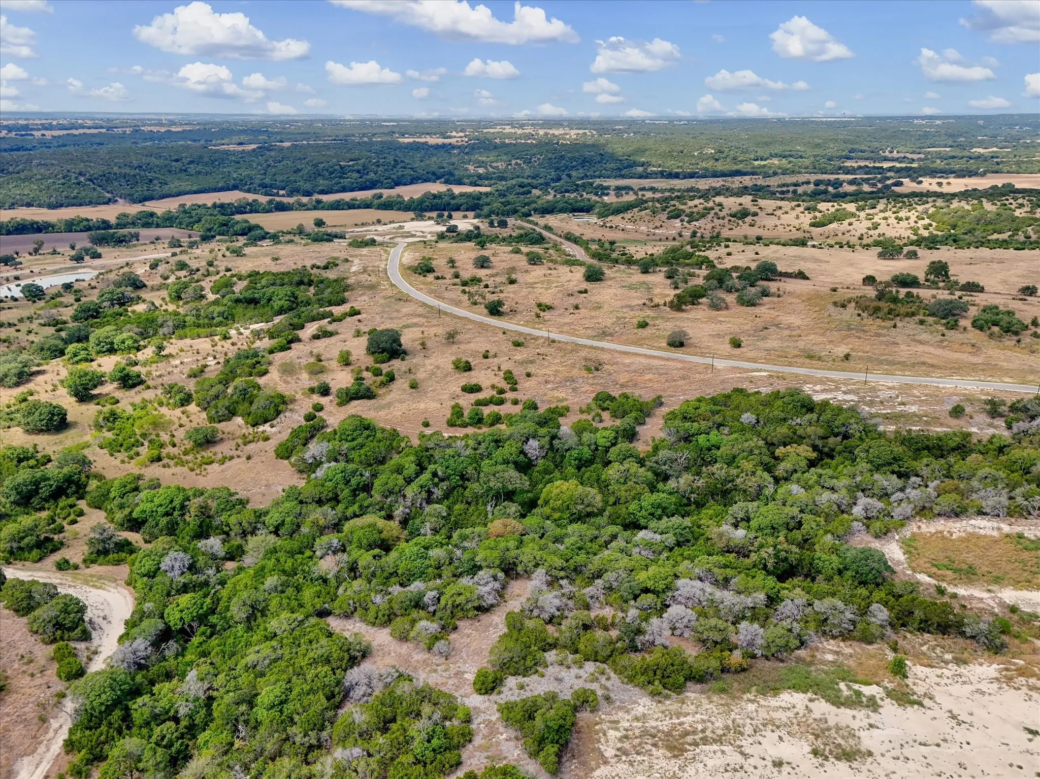 Expansive undeveloped land featuring diverse natural vegetation, varying terrain, and visible unpaved roads