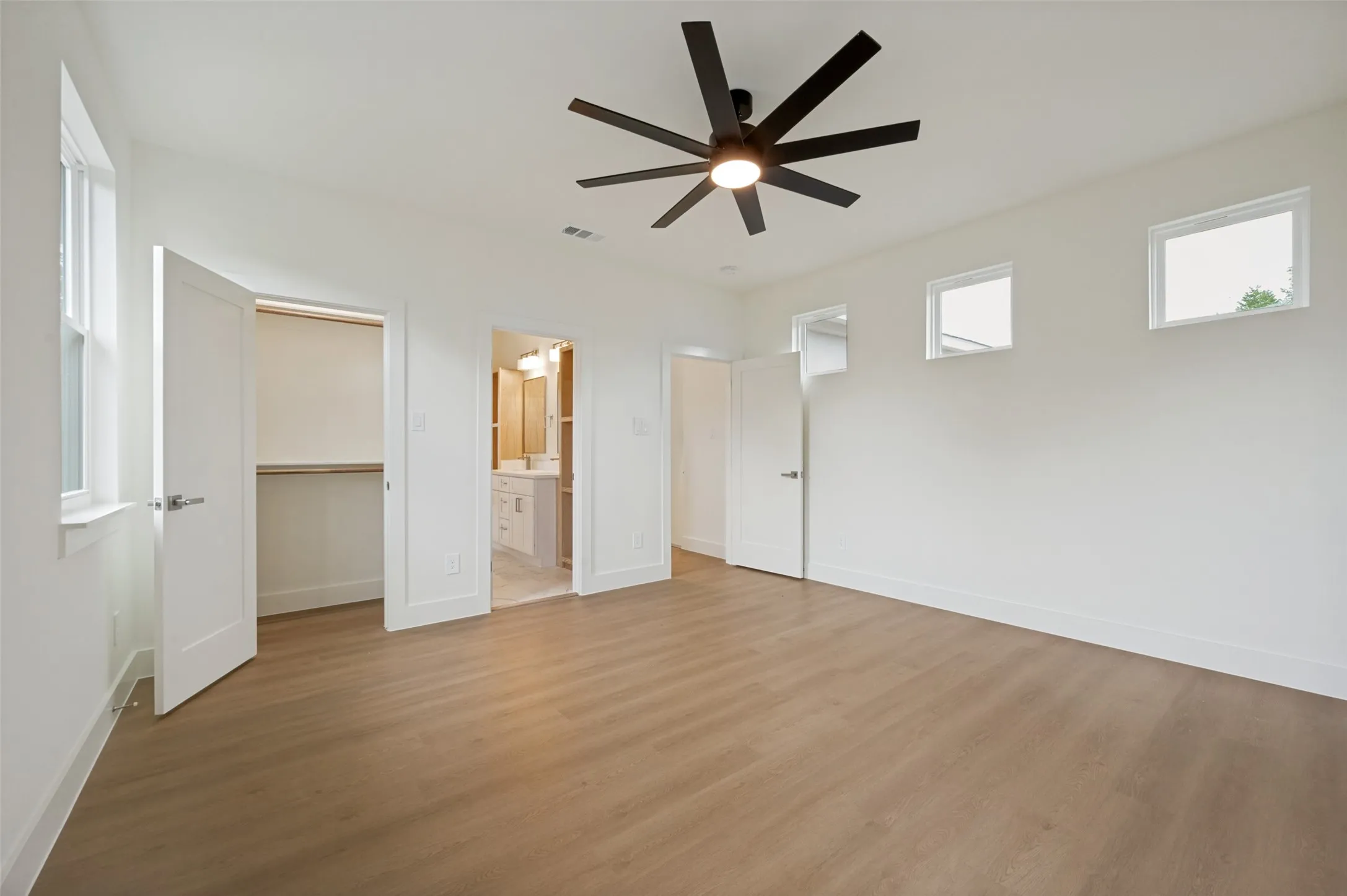Spacious room featuring wood-finish flooring, a modern ceiling fan, recessed lighting, and multiple windows