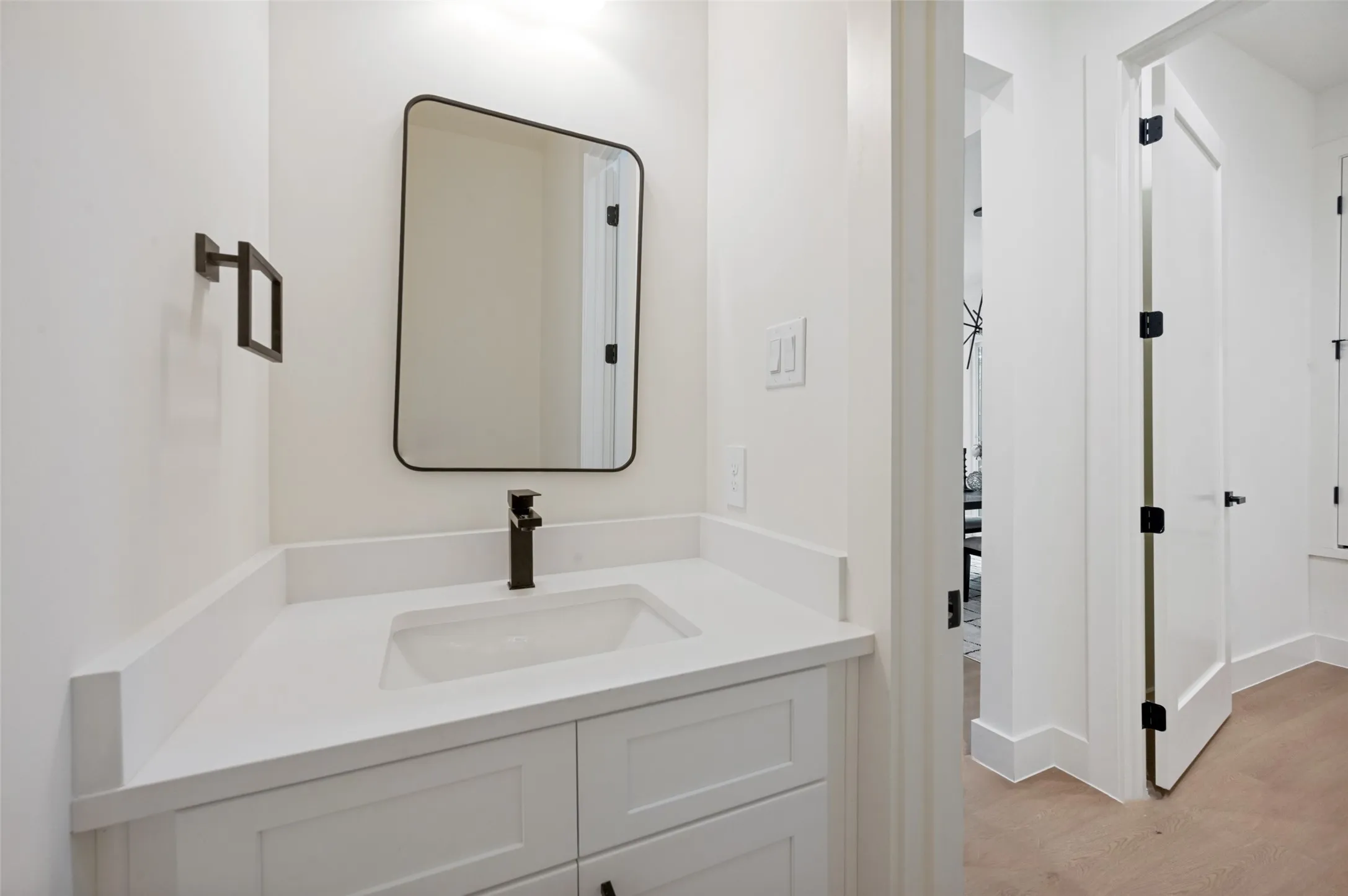 White vanity with shaker-style cabinetry, an integrated sink, and a matte black single-handle faucet