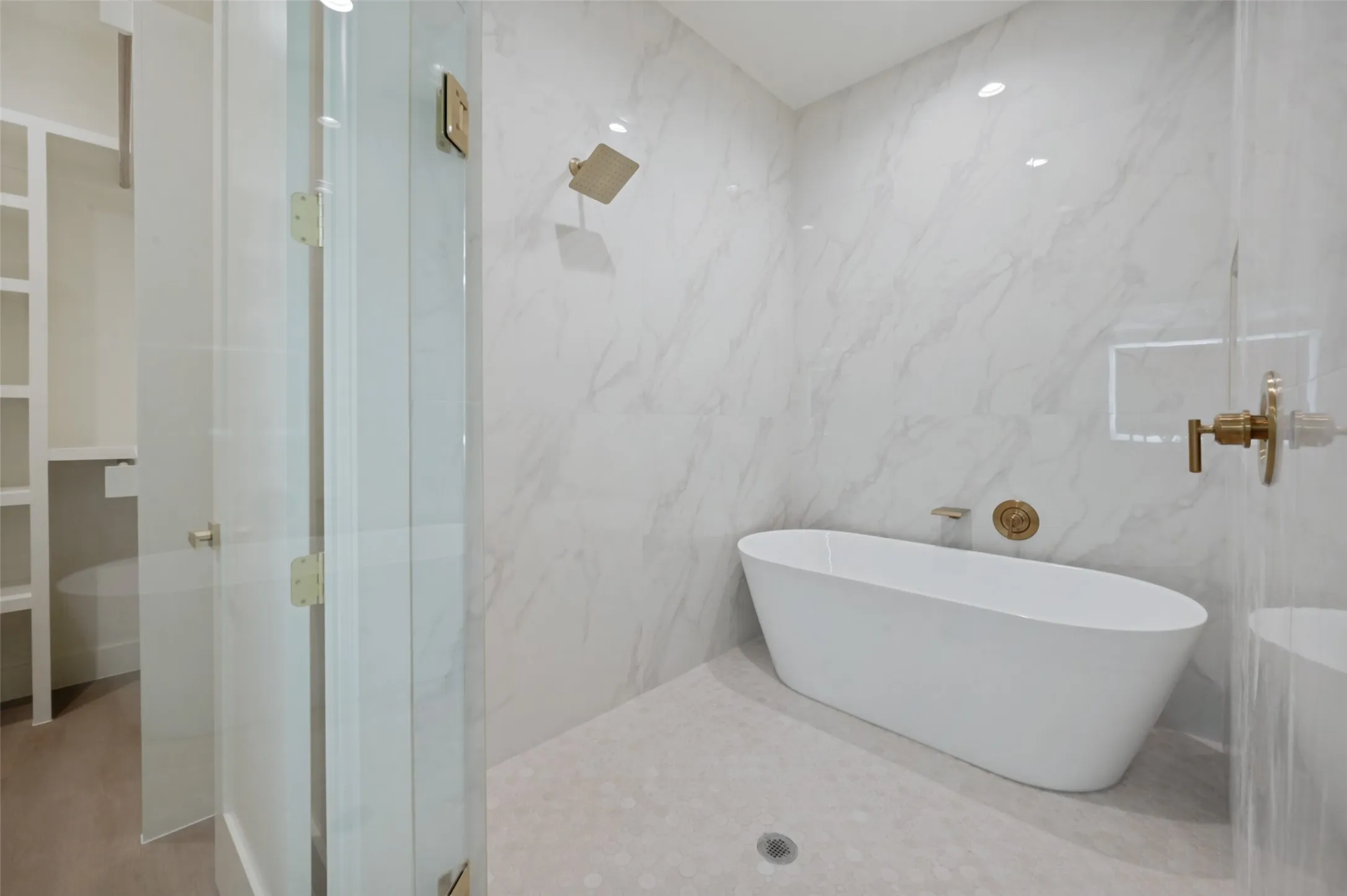 Freestanding soaking tub, large format tile shower surround, and gold-finish fixtures
