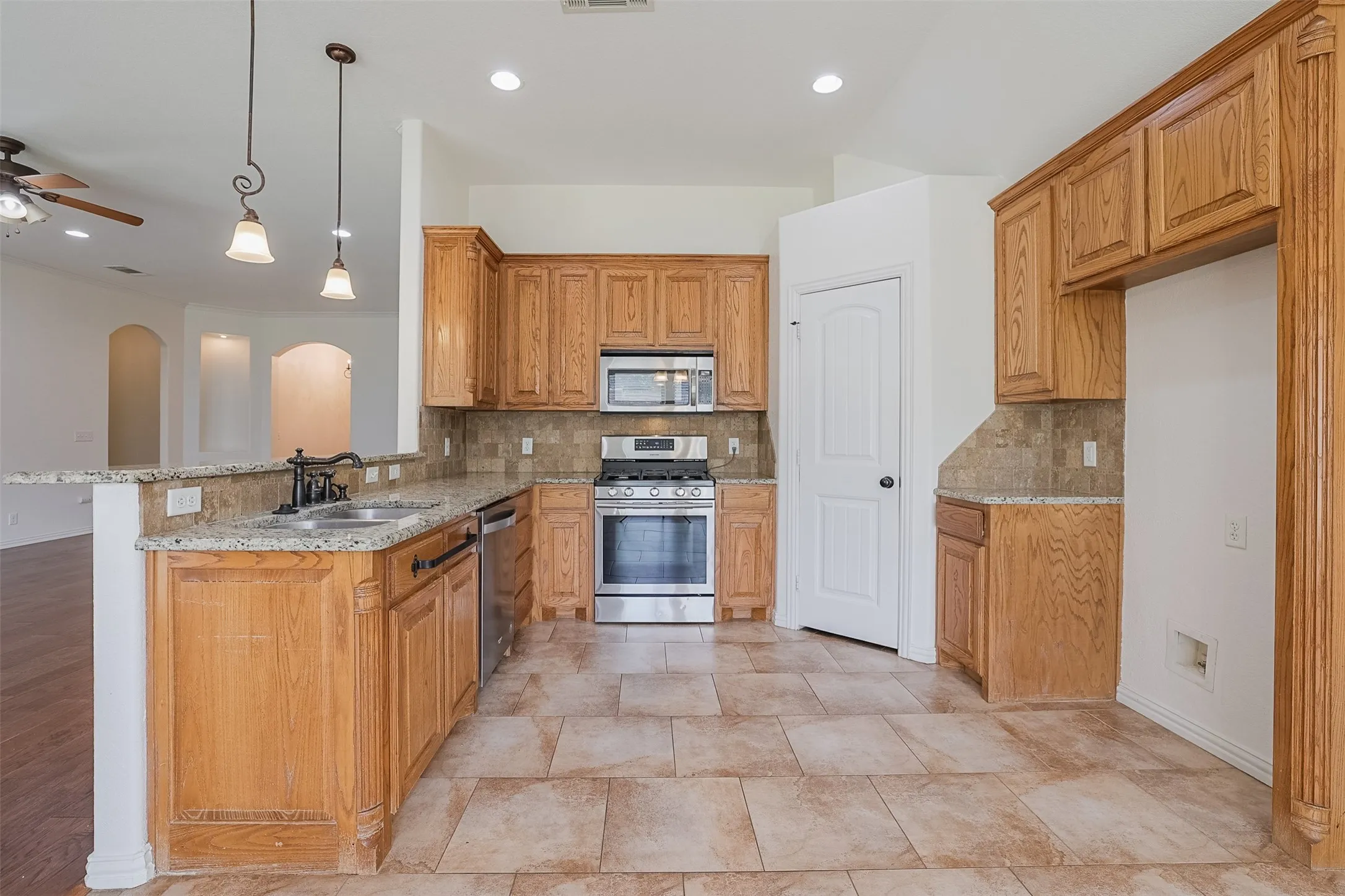 Kitchen featuring wood cabinetry, granite countertops, stainless steel appliances, tile flooring, and recessed lighting