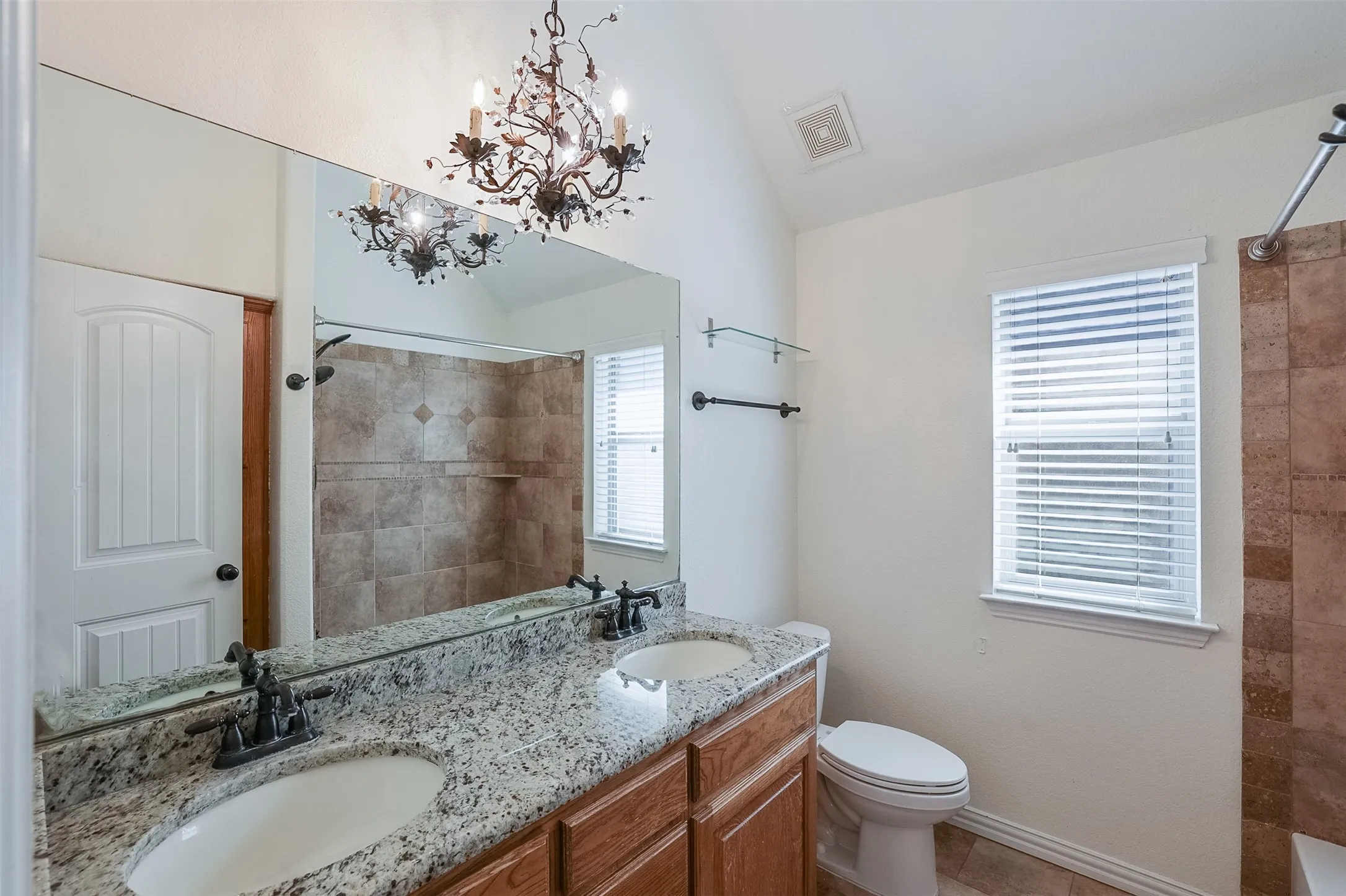 Double vanity with undermount sinks, granite countertop, and wood-finish cabinetry