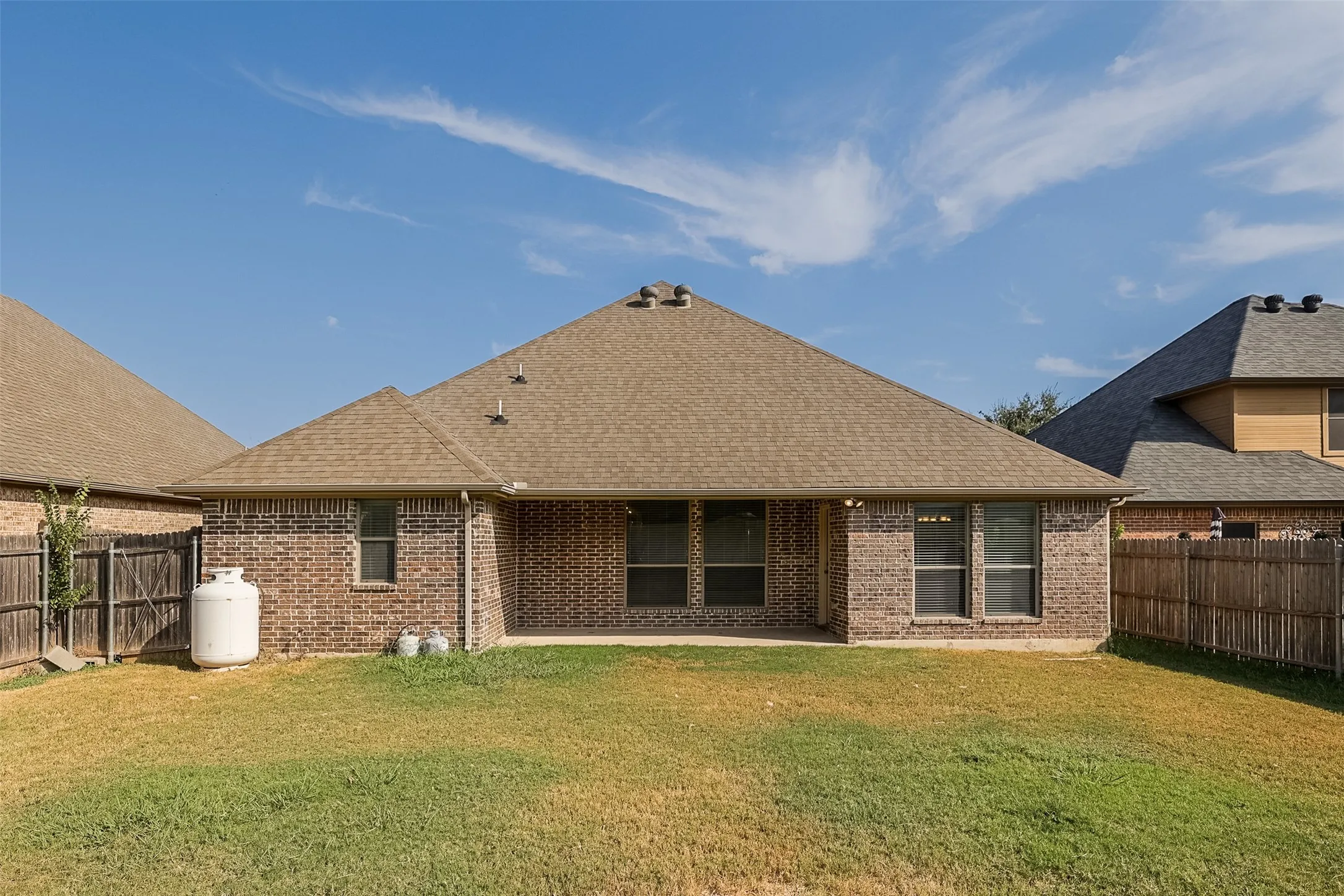 Brick exterior with a brown shingle roof and covered patio