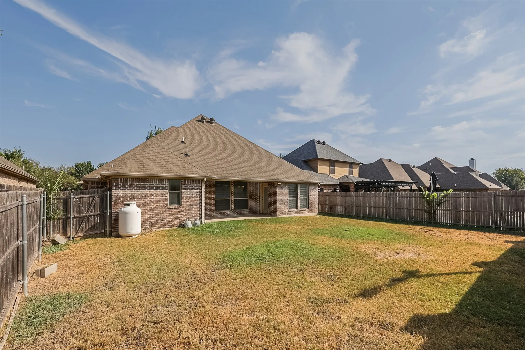 Brick exterior featuring a gabled roofline, private fencing, and an expansive yard