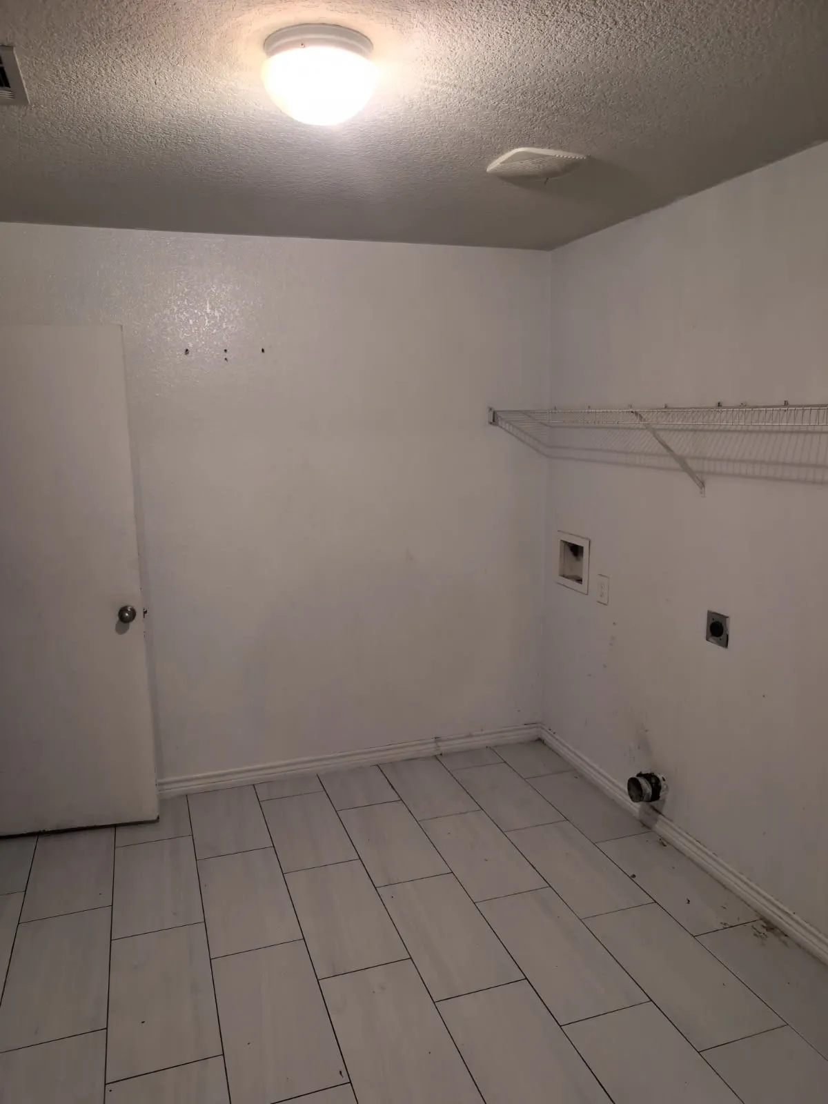 Tile flooring with a rectangular pattern, white walls, and a built-in wire shelving unit