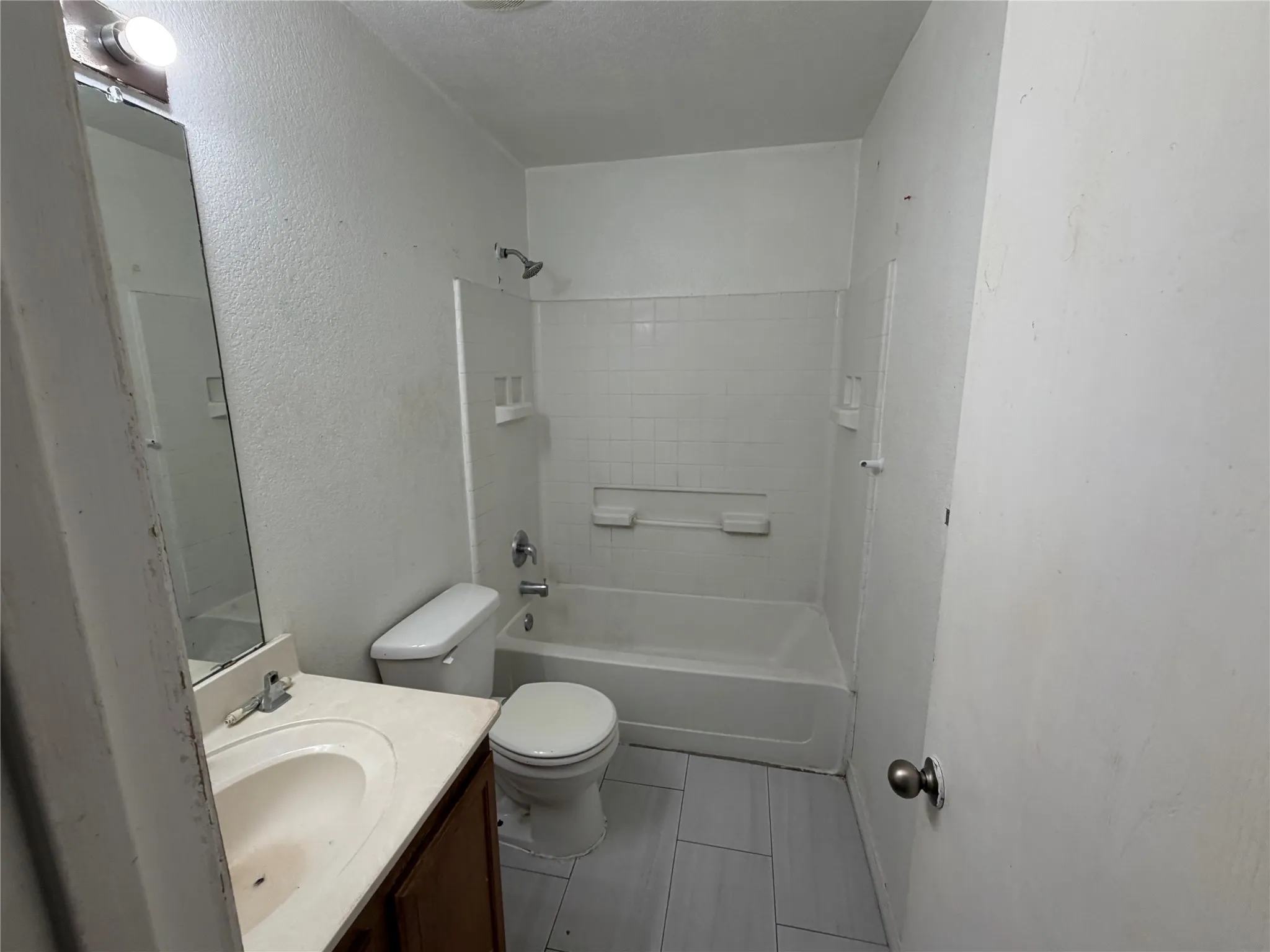 Bathroom featuring a shower-tub combination, vanity with integral sink, and tile flooring