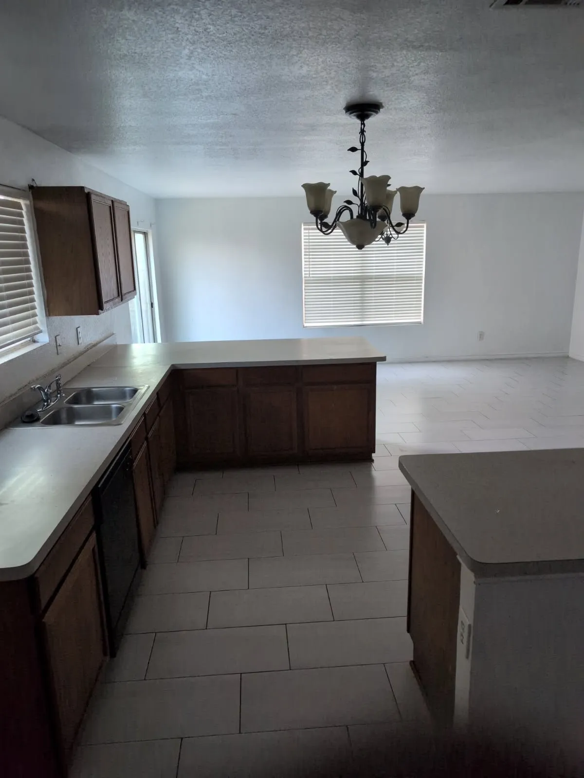 Kitchen with light-toned tiled flooring, wood-finish cabinetry, and a double basin sink