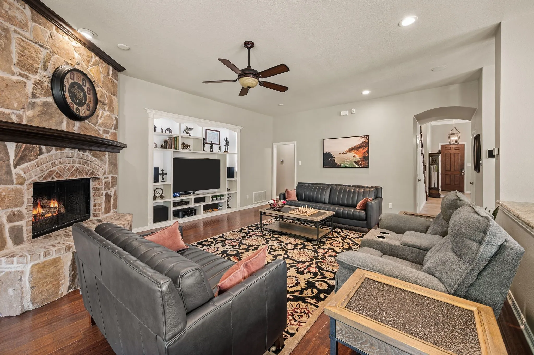 Generously sized living room offers comfortable seating space, built-ins & a beautiful floor-to-ceiling stone fireplace.