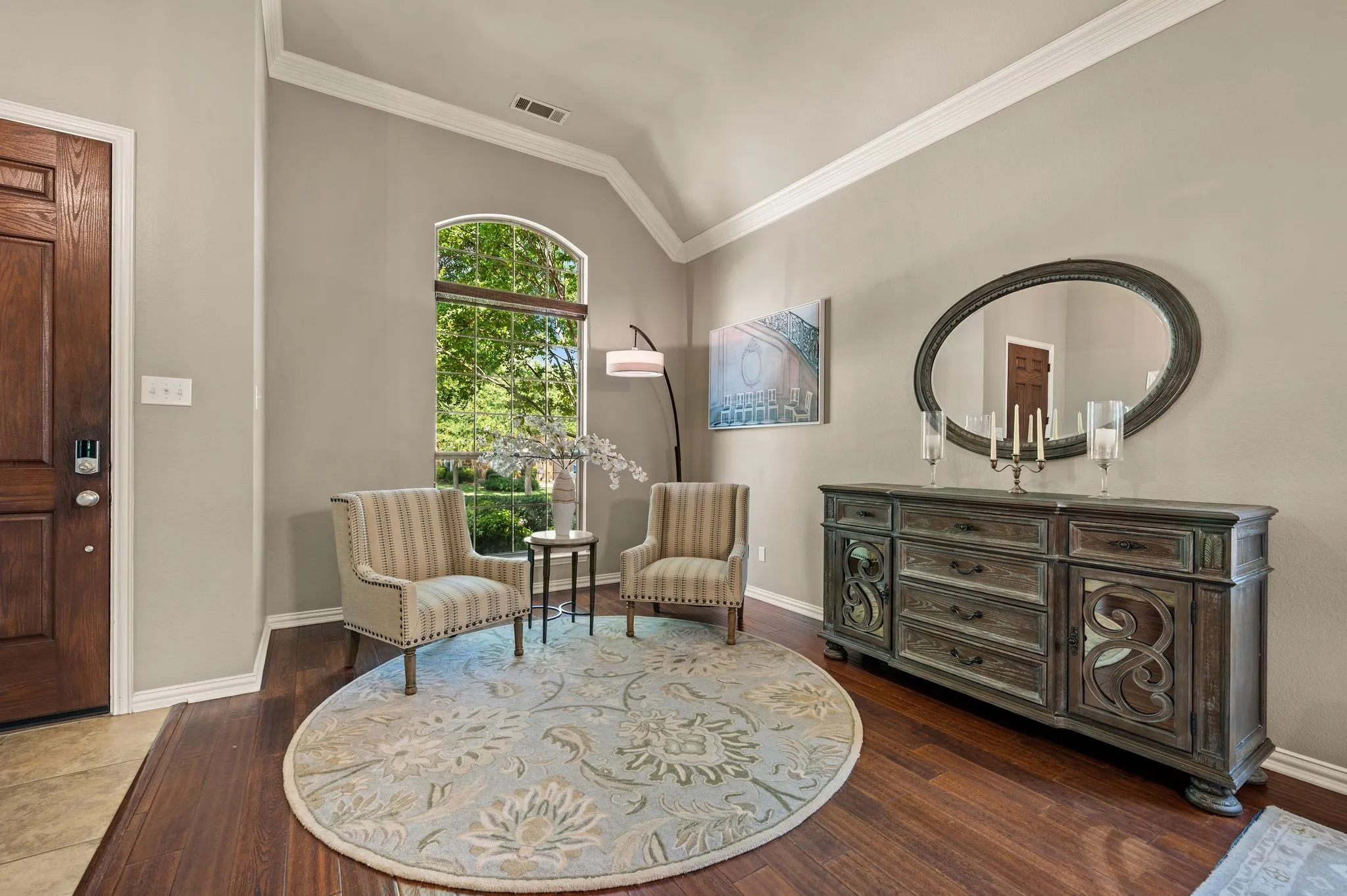 Inviting formal living area features a vaulted ceiling, oversized arched window & abundant natural light.  A prior owner used this space as a living area, so there are TV backet holes behind the art handing on the wall.