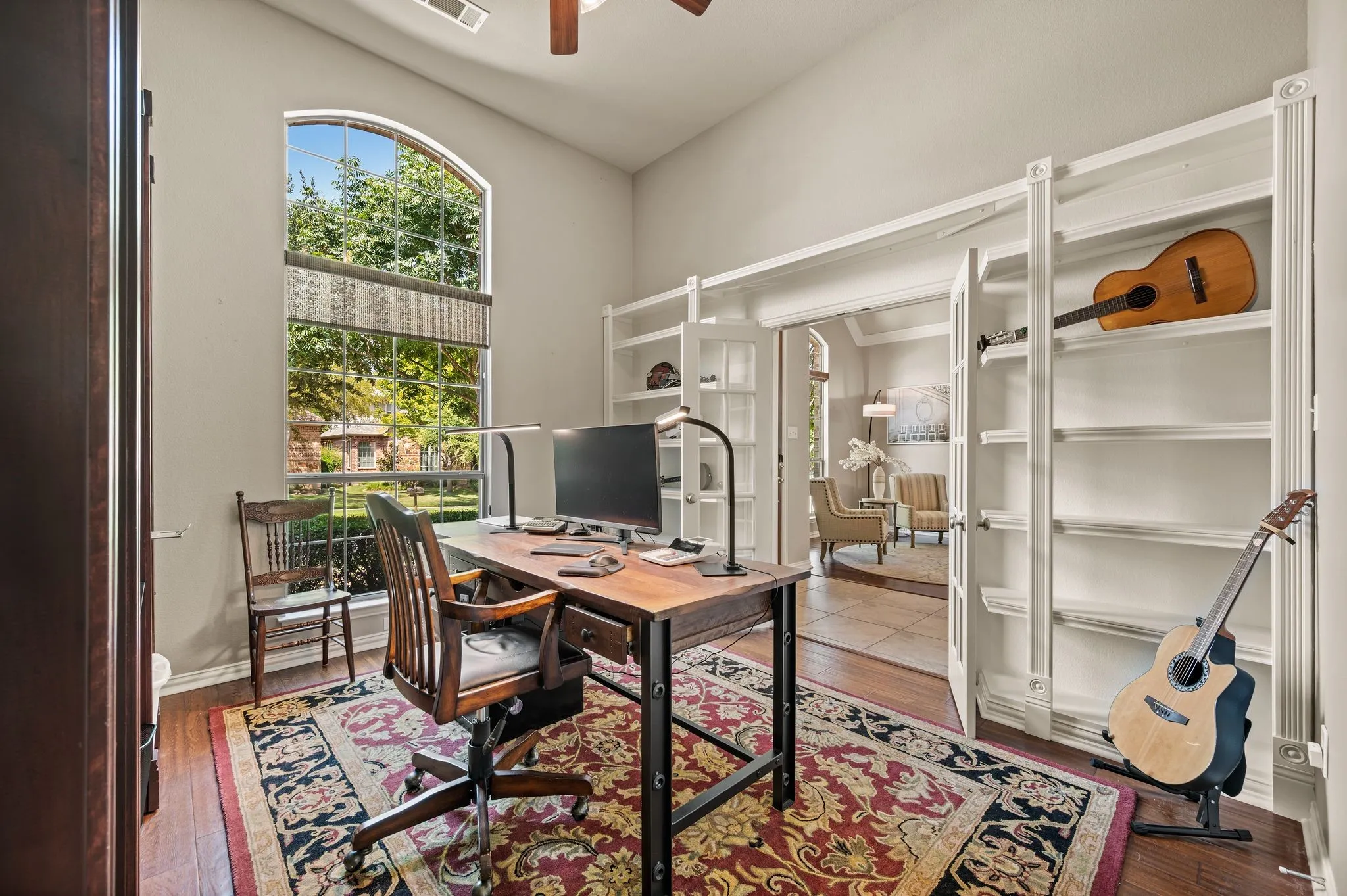 Private home office with French doors, built-in shelving, wood flooring & a large arched window. This room has a walk-in closet so it could be used as an additional bedroom if desired!