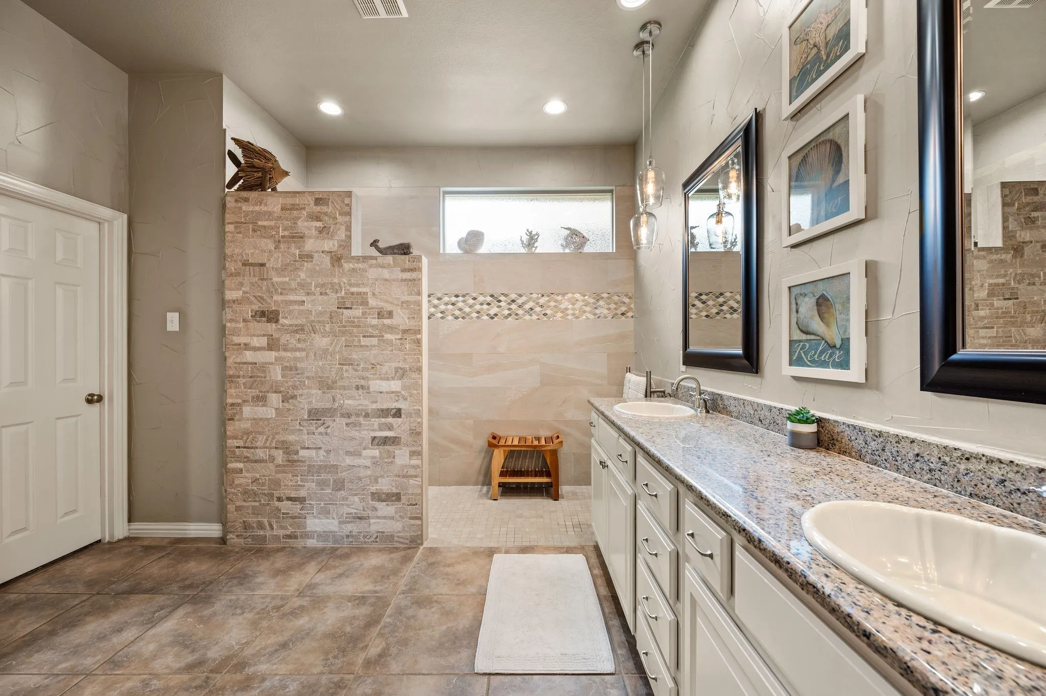 Updated primary bathroom features a custom oversized "no-step" walk-in shower, dual sinks, granite countertops & extensive cabinetry.