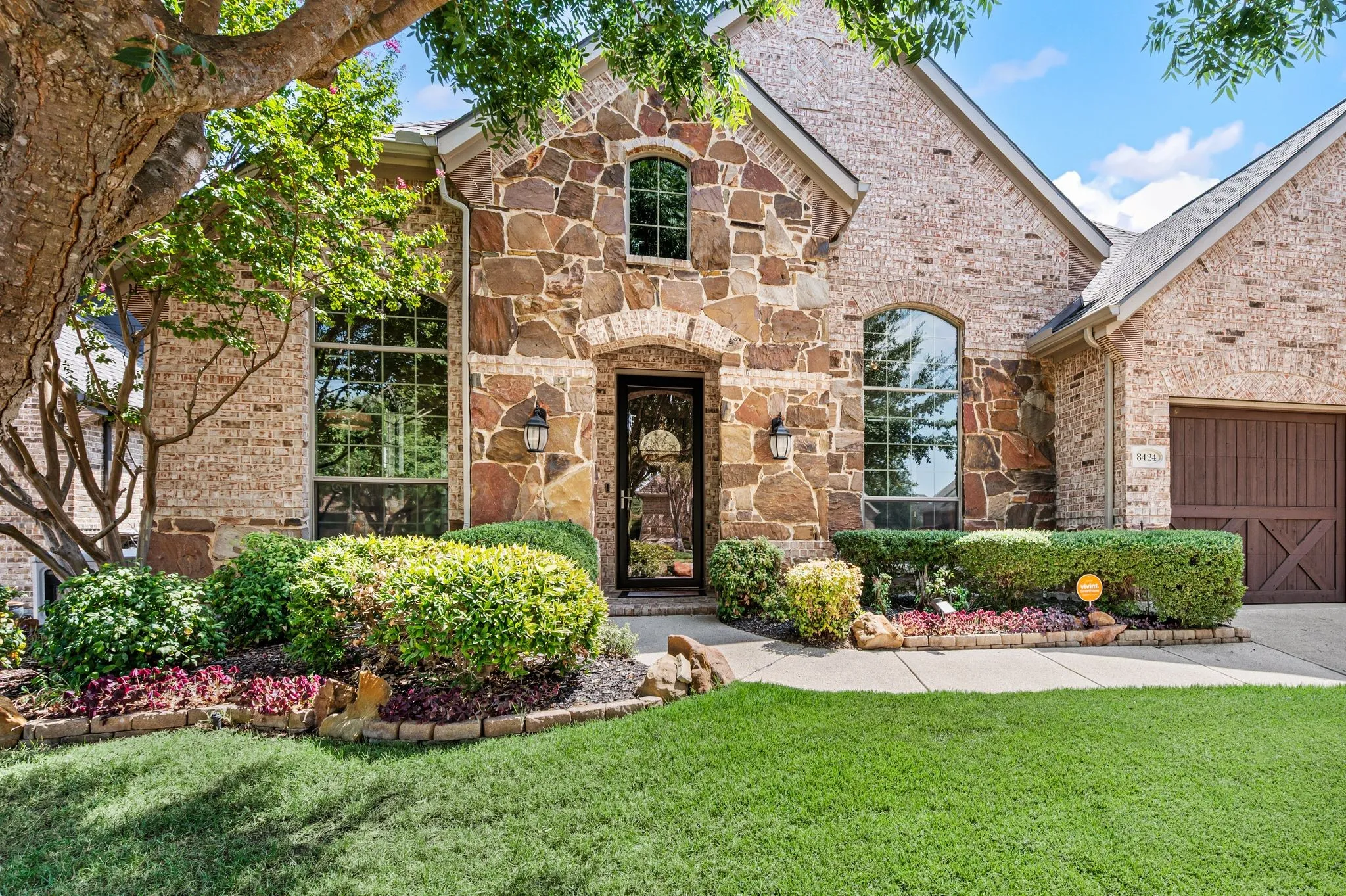 Gorgeous curb appeal with mature landscaping, arched windows & a welcoming stone-framed entry.